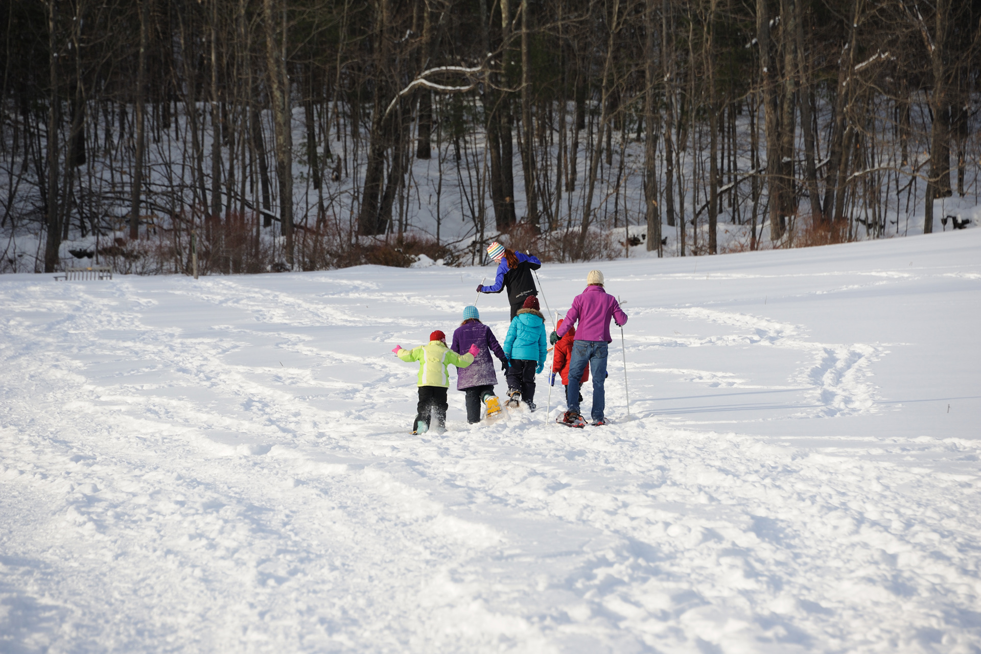 A family on snowshoes in a field at Wachusett Meadow