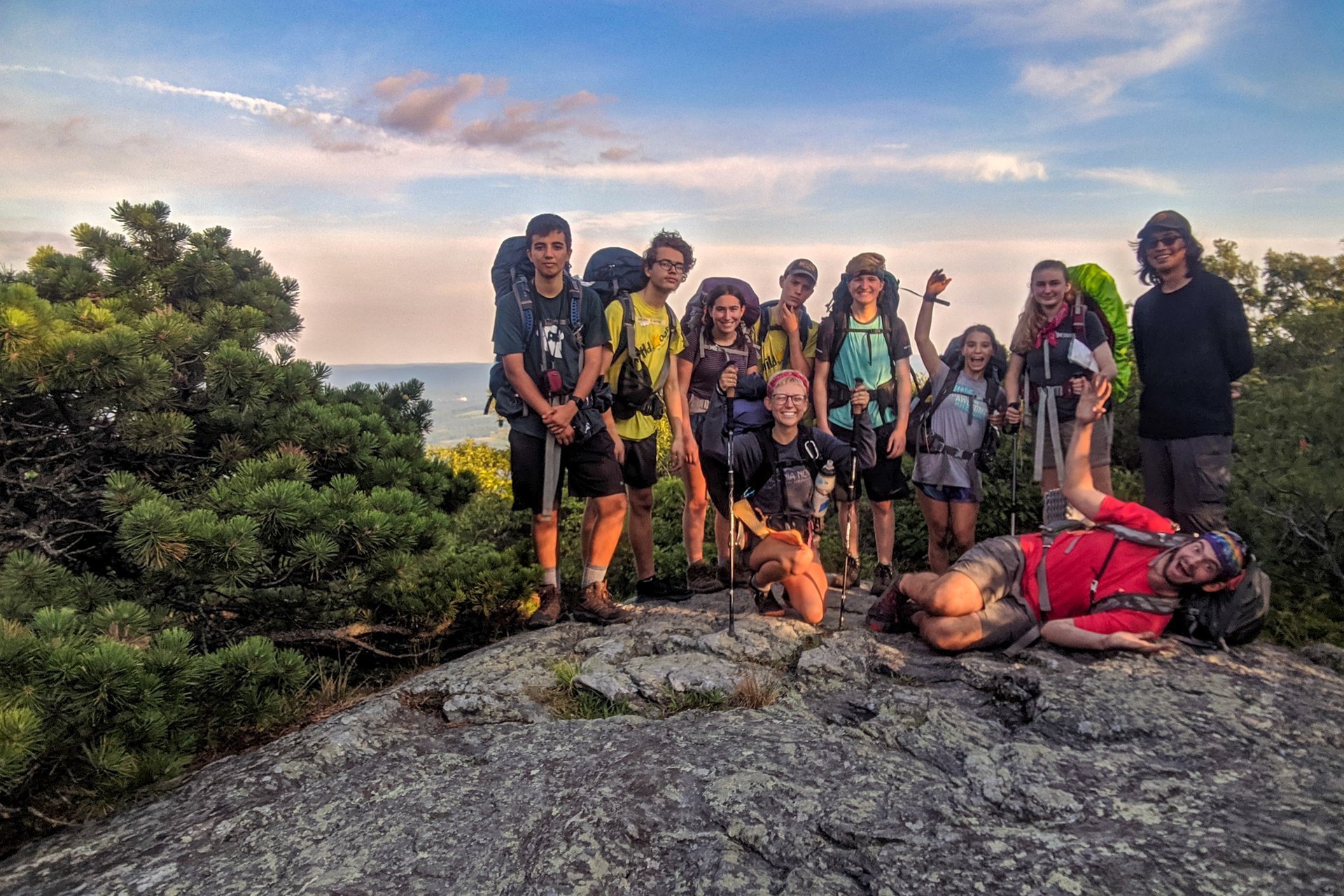 group of teens on top of a mountain wearing backpacks