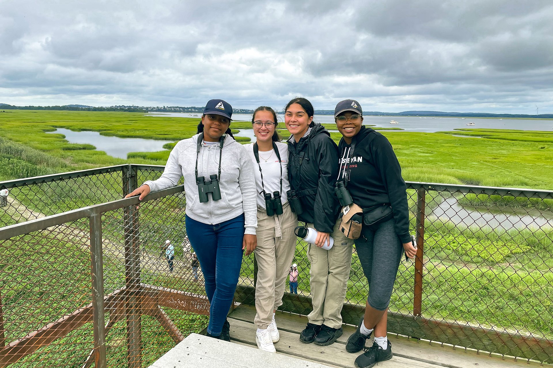 Four members of climate corps on a platform in front of marsh