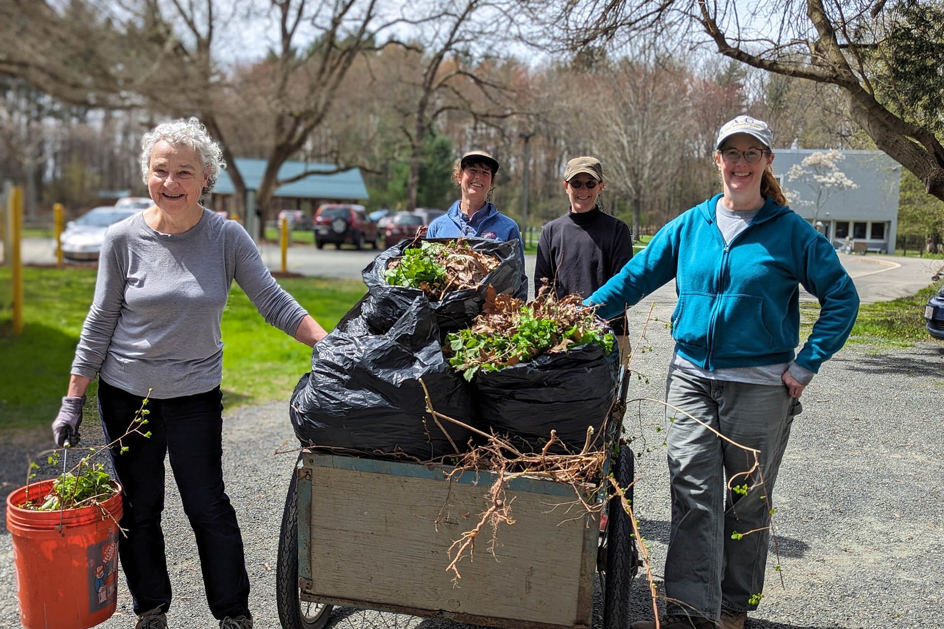 Four volunteers moving bags of debris in a cart