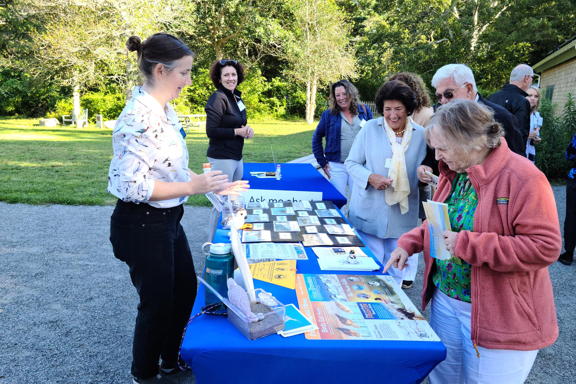 Attendees stopping by a table with image and info cards laid out on top