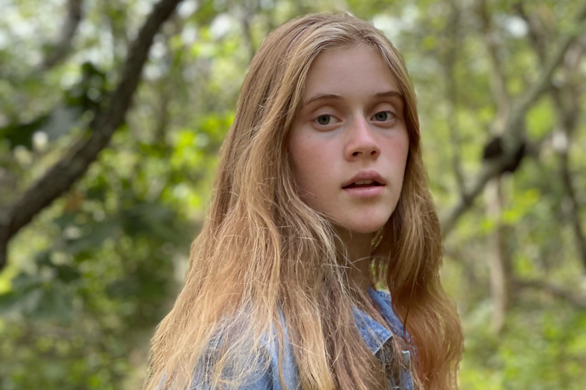 Young girl with long blonde hair looking at the camera.