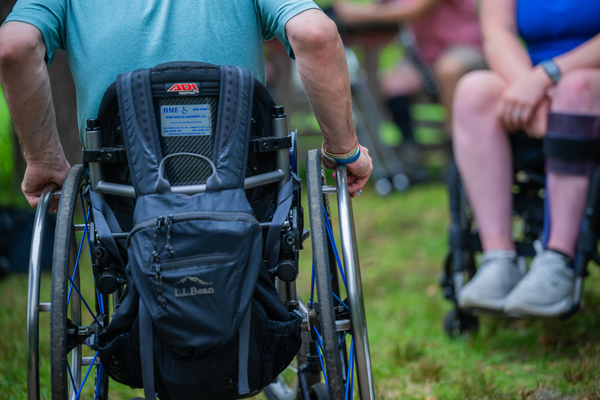 Two people in wheelchairs on green grass
