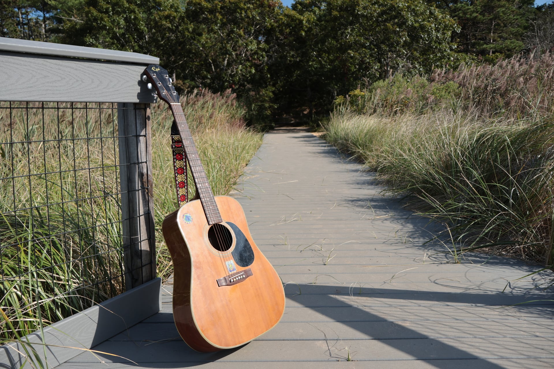 Guitar resting against a boardwalk railing