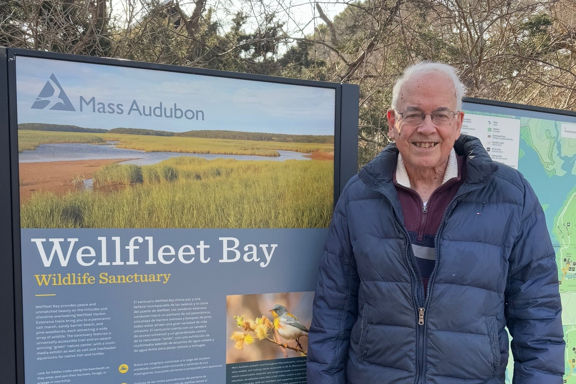 Wellfleet Bay volunteer Chuck Dow next to an informational sign