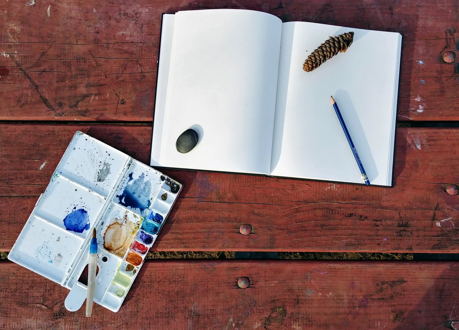 overview image of paint on a plastic palette and blank notebook