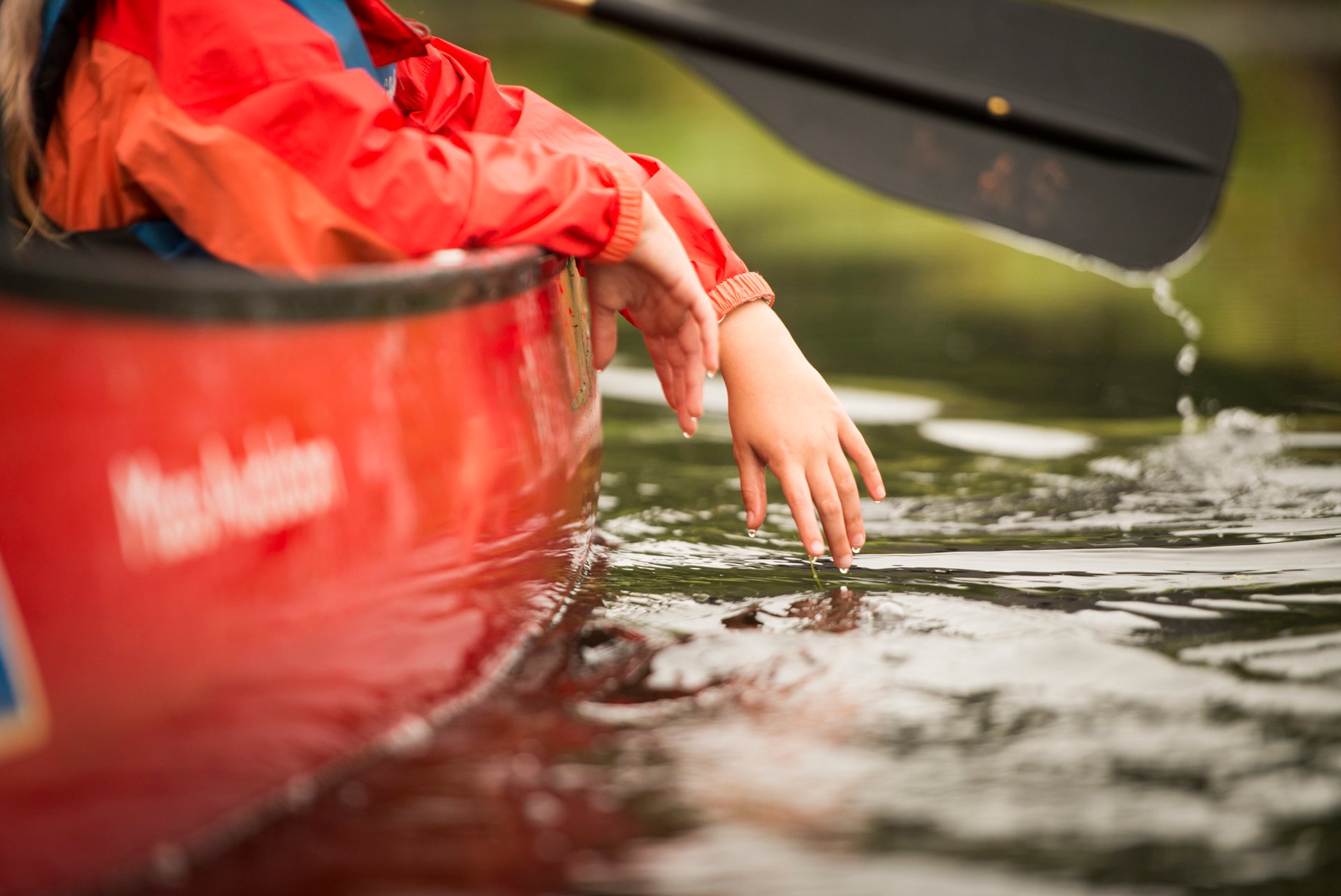 Hands feeling water on edge of canoe