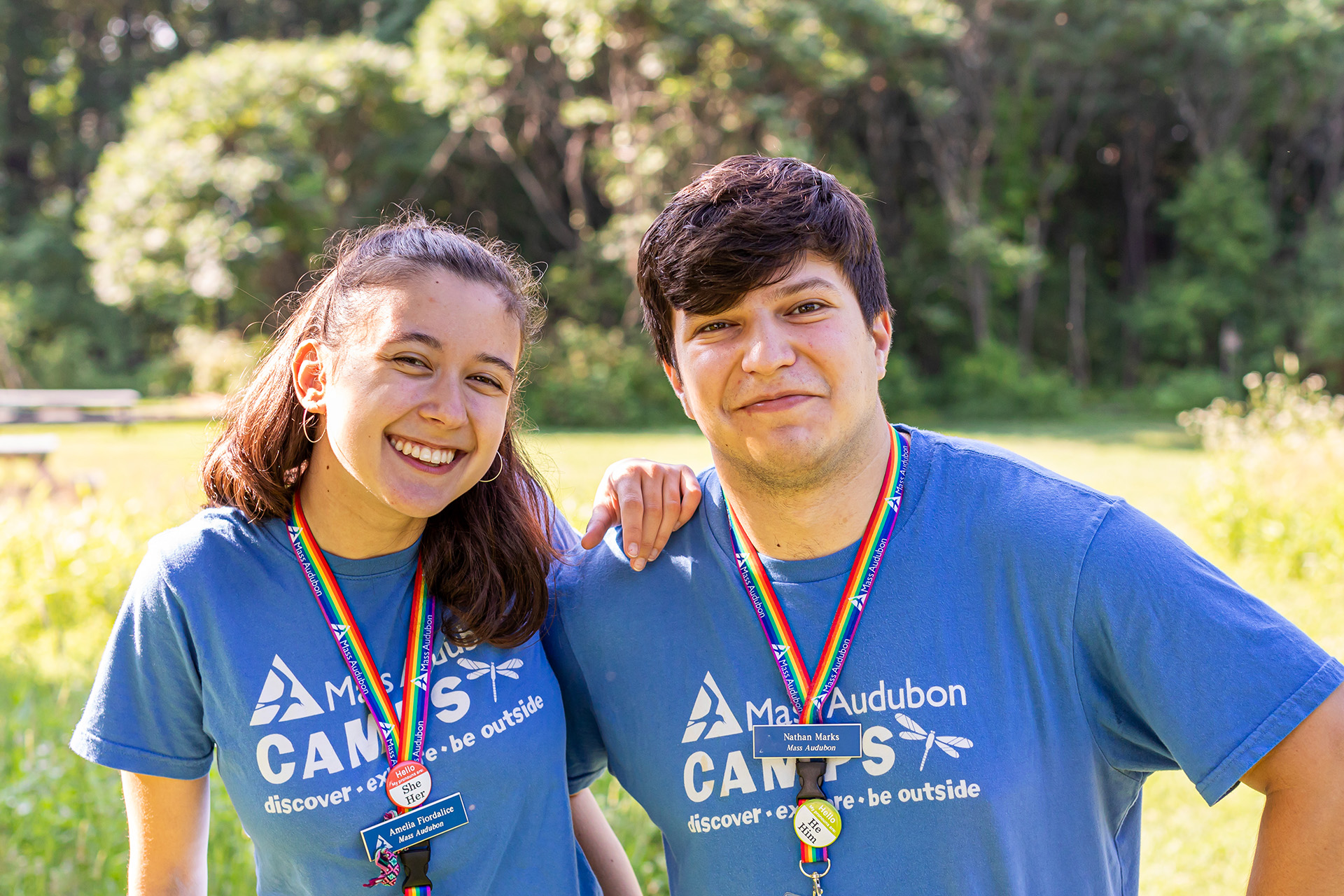 Two young adults in blue t-shirts posing for a photo