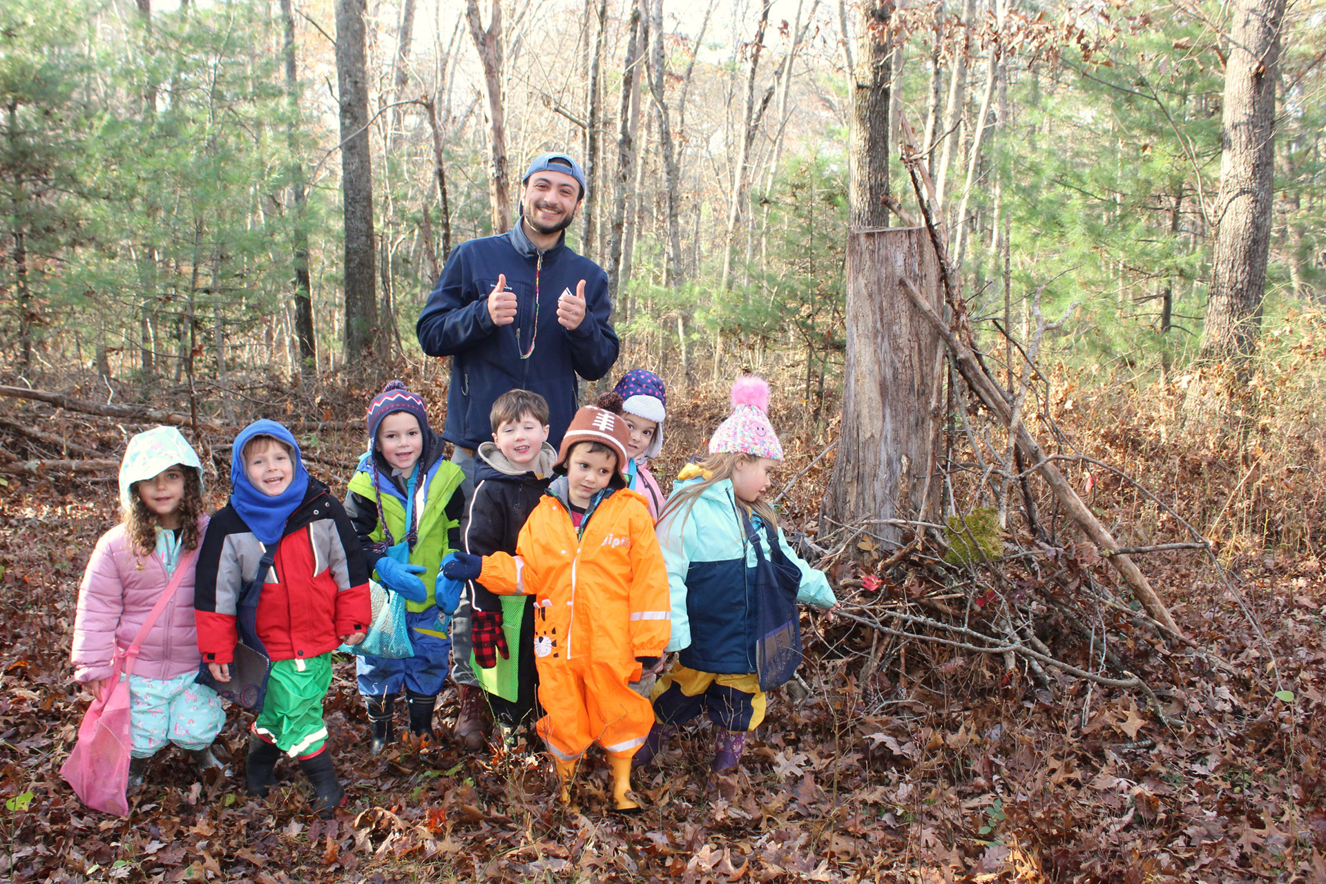 Chris Bretti and class posing for a group photo against a forest in the background