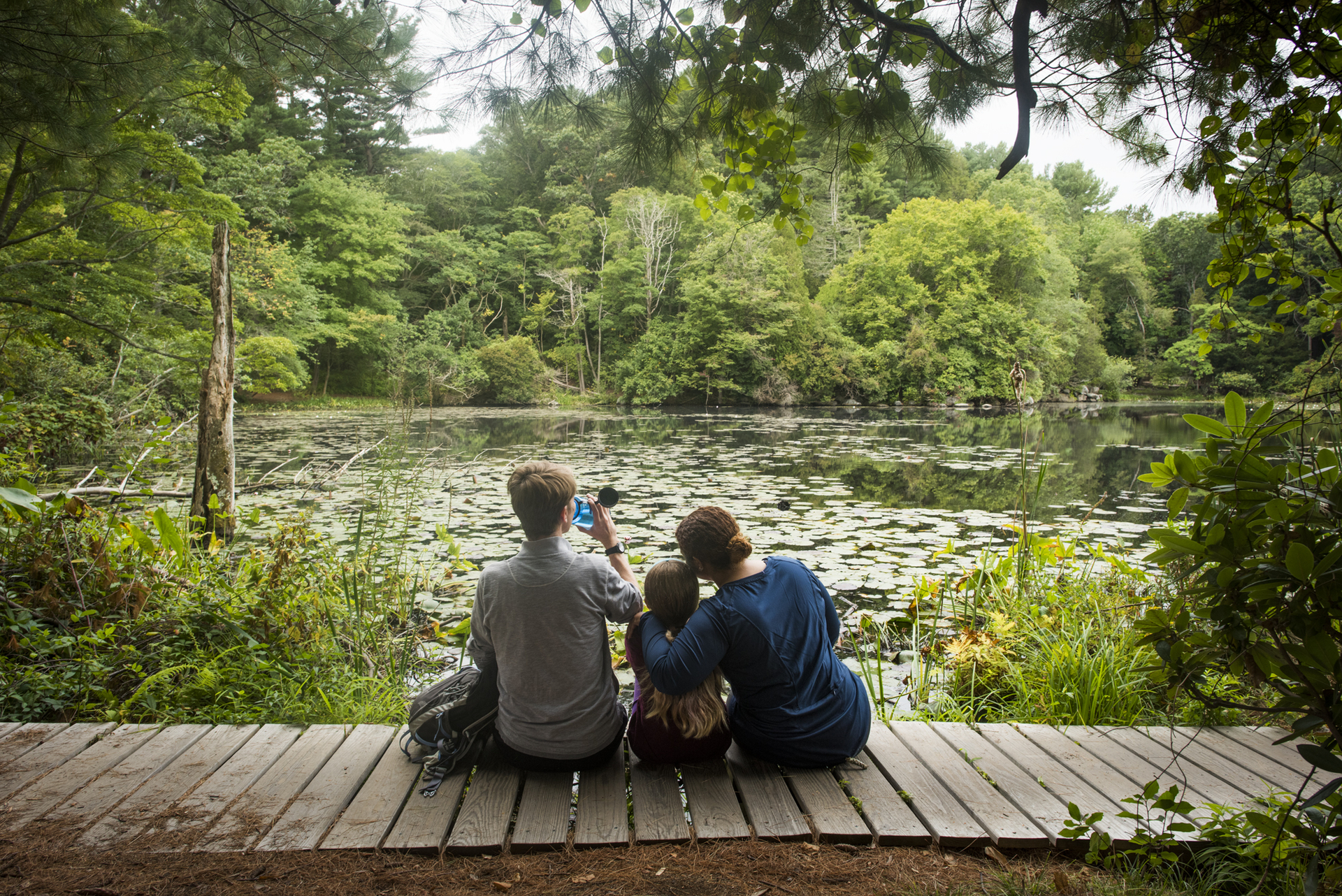 Family resting on Ipswich River's boardwalk in summer