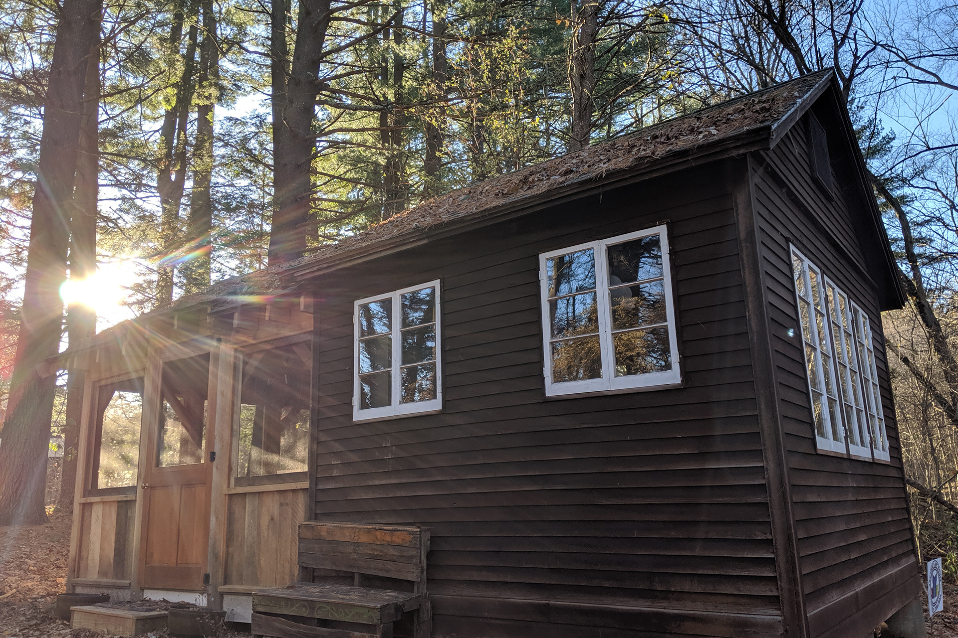 Arcadia's Art House, a log cabin seen with the sun behind it