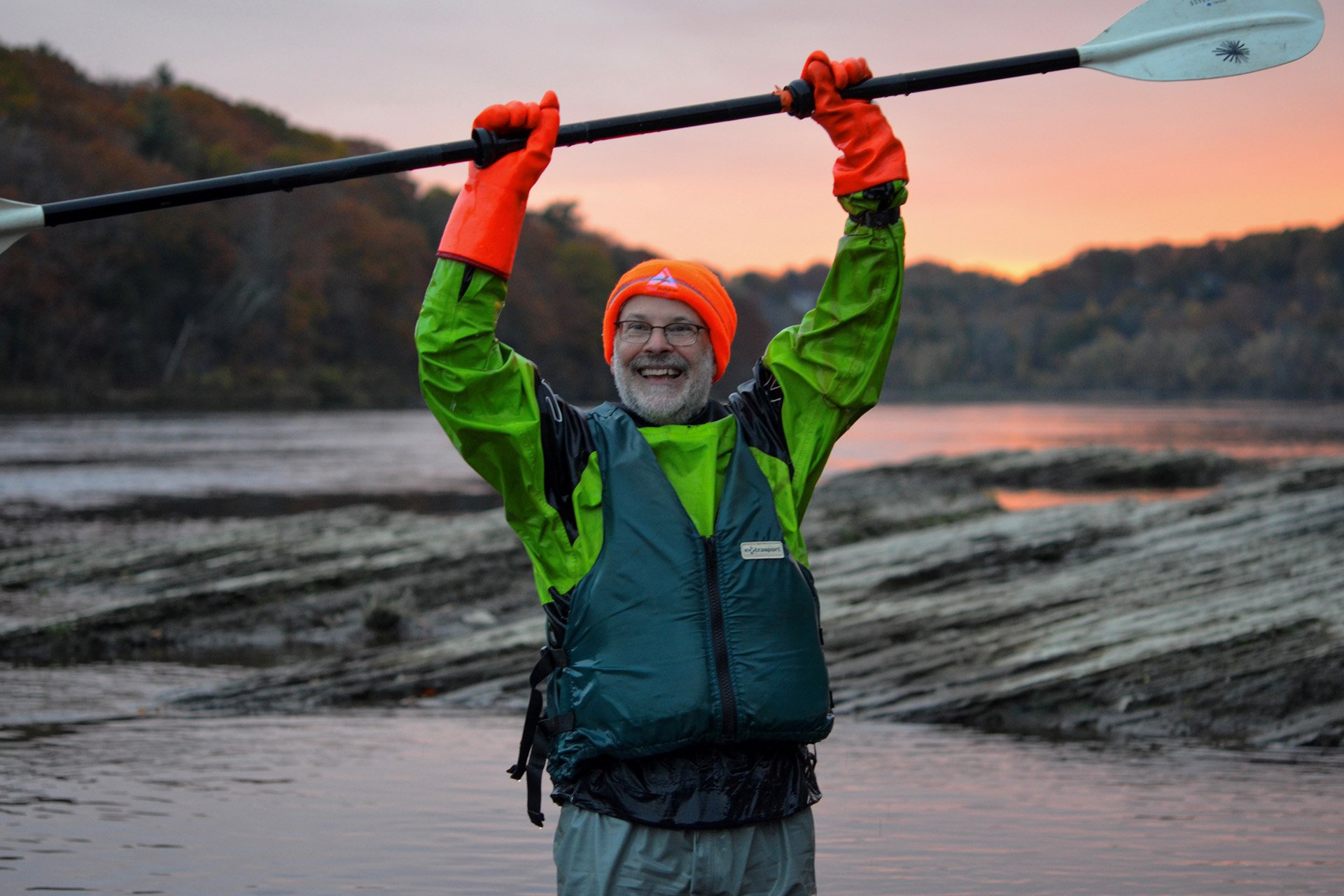 Dave Rothstein smiling and holding a double-ended paddle above his head