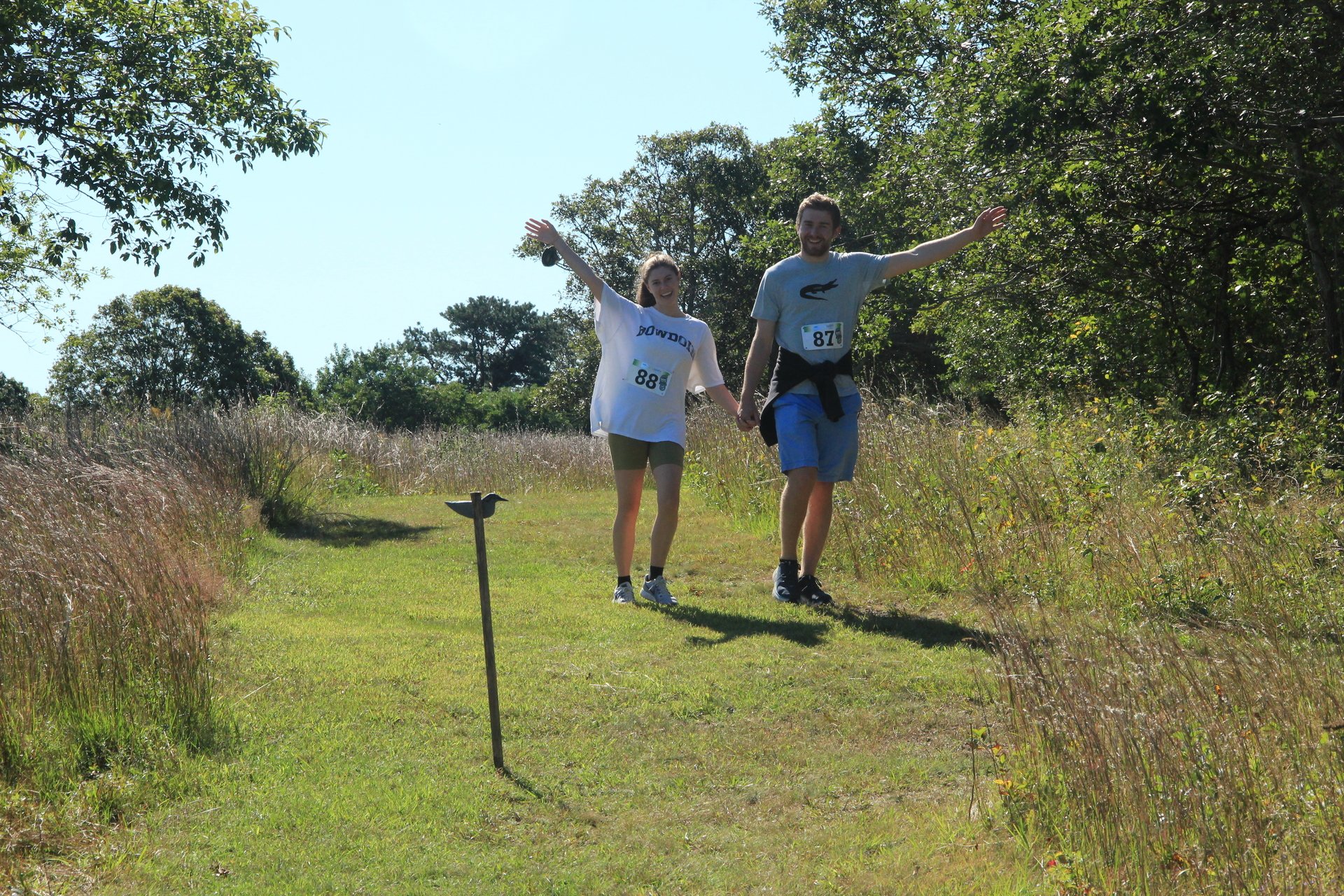 Two runners holding hands and waving toward the camera