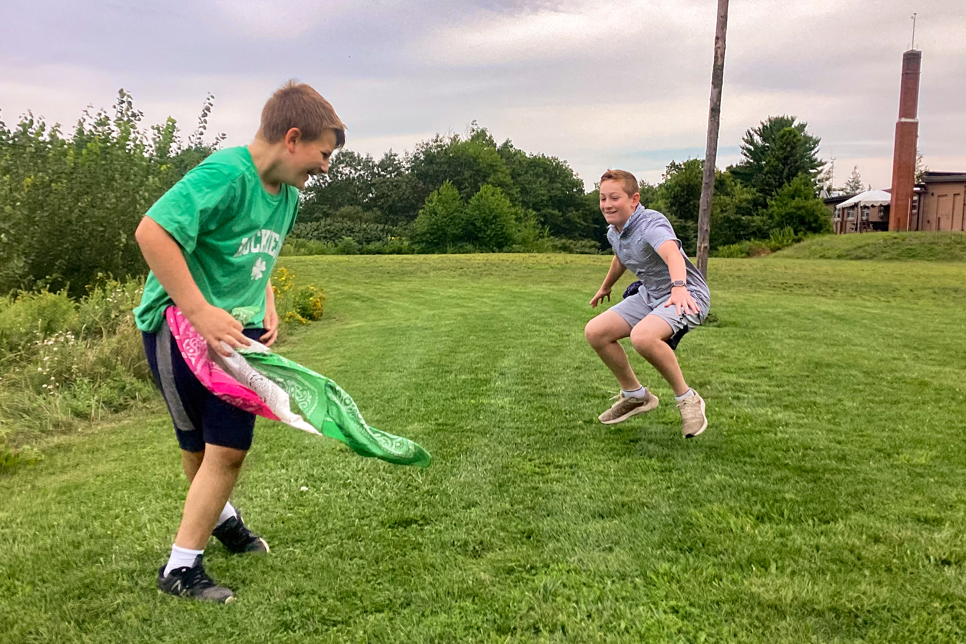 Two Blue Hills campers playing a game of tag in the grass