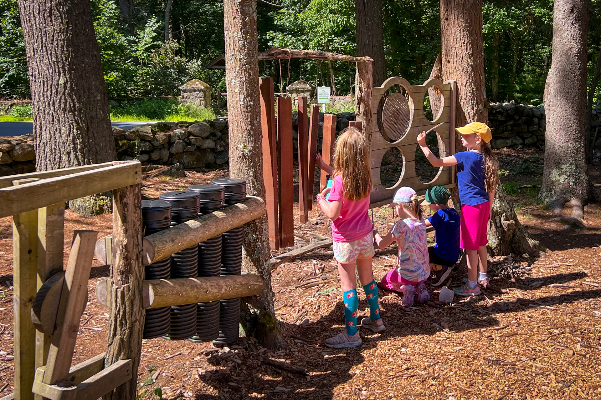 A group of campers plays the outdoor musical instruments in Moose Hill's Nature Play Area