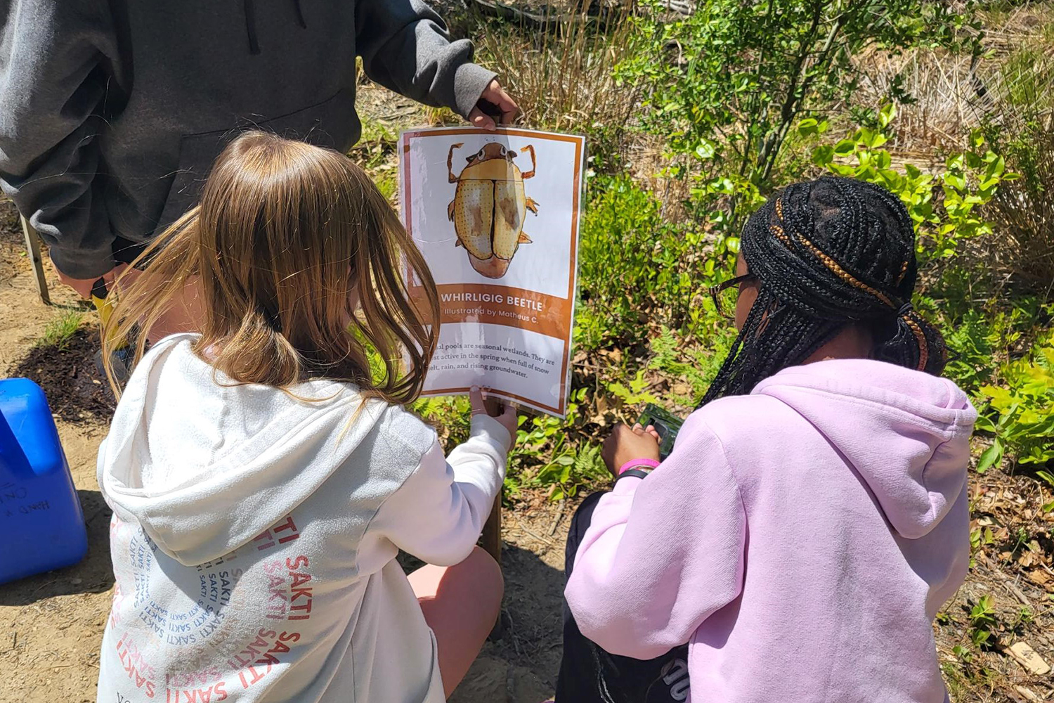 Two students hanging a sign on a stake