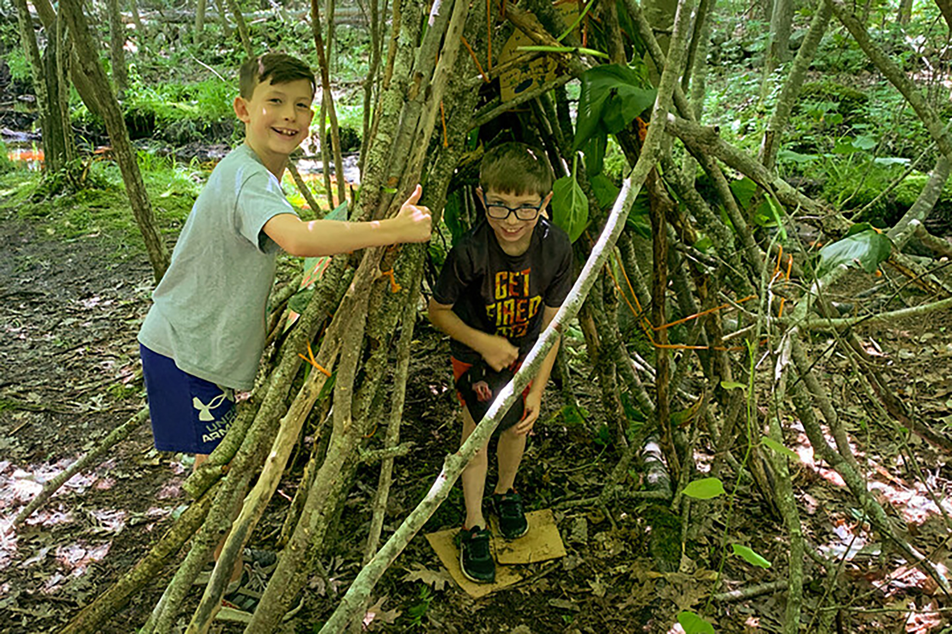 Campers with a fort they built out of sticks