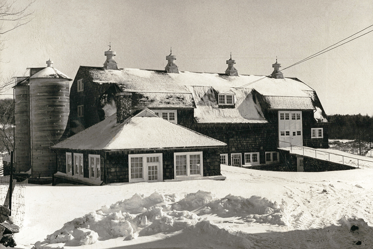Black and white photo of historic barn during winter with snow on the ground