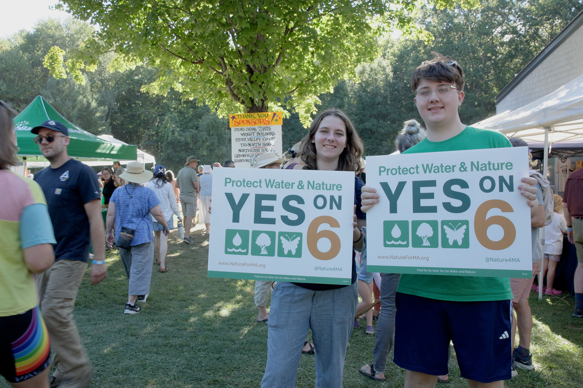 Two people holding Yes on 6 signs at an outdoor event