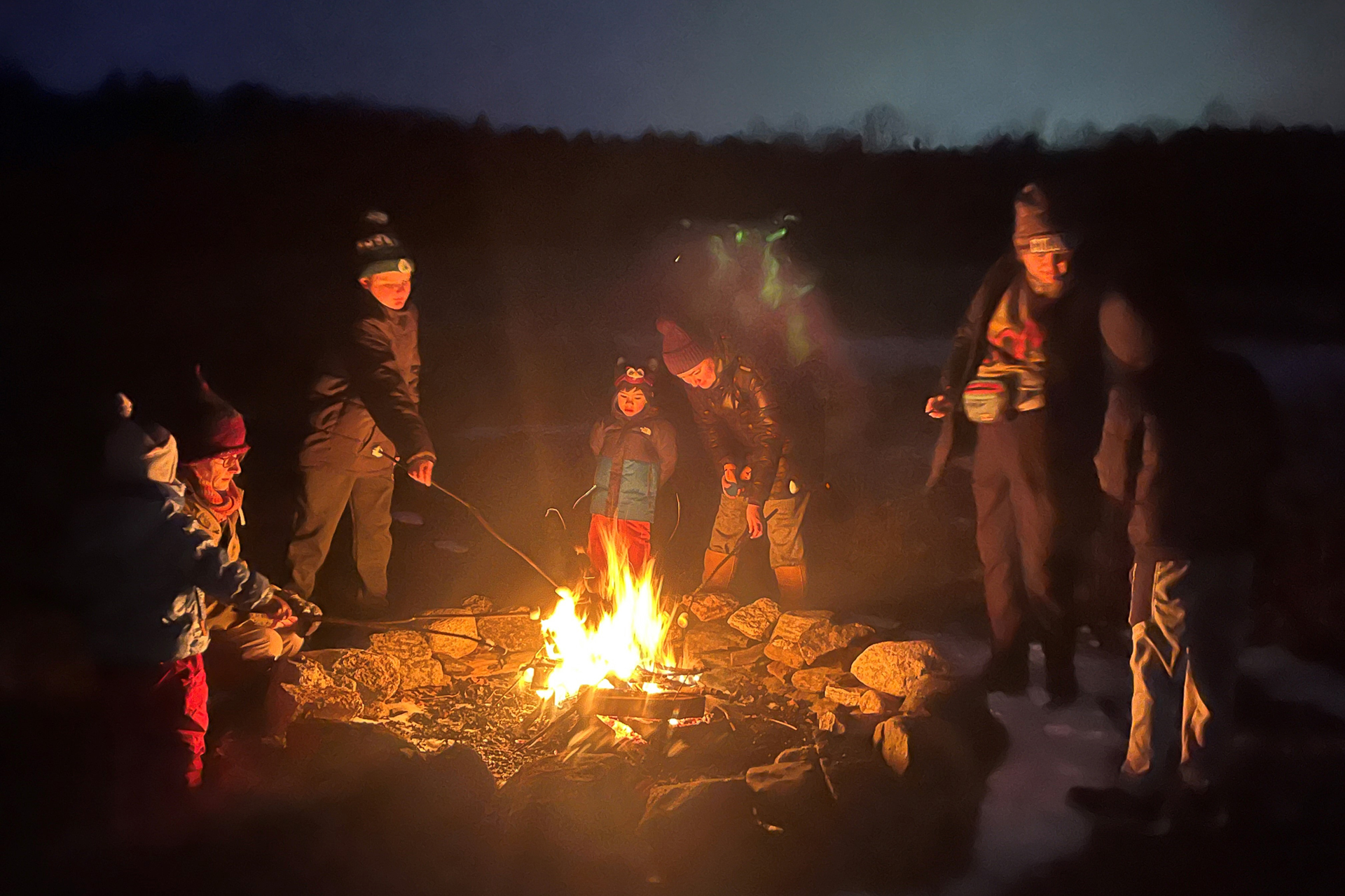 Roasting marshmallows around a fire pit on a winter night