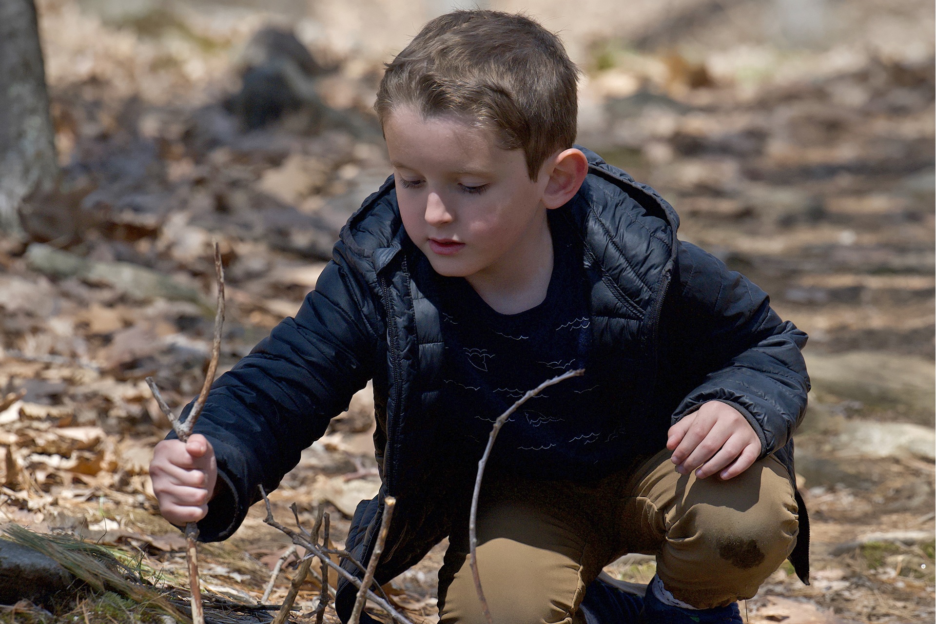 Young child building a "fairy house" out of sticks