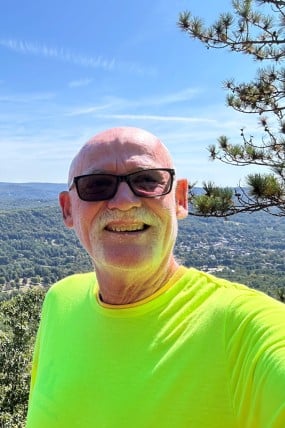 Andy Tolland smiling at camera with scenic view in back