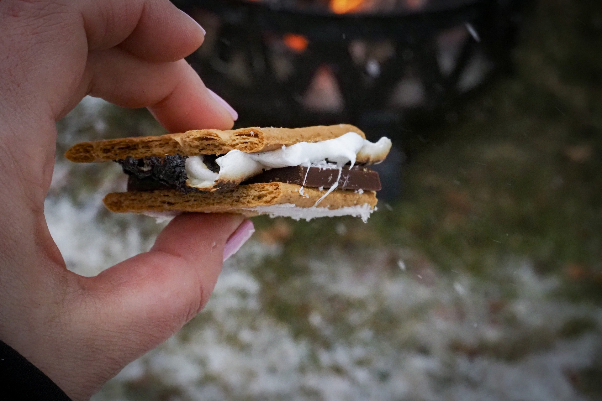 Gooey s'more held between two fingers