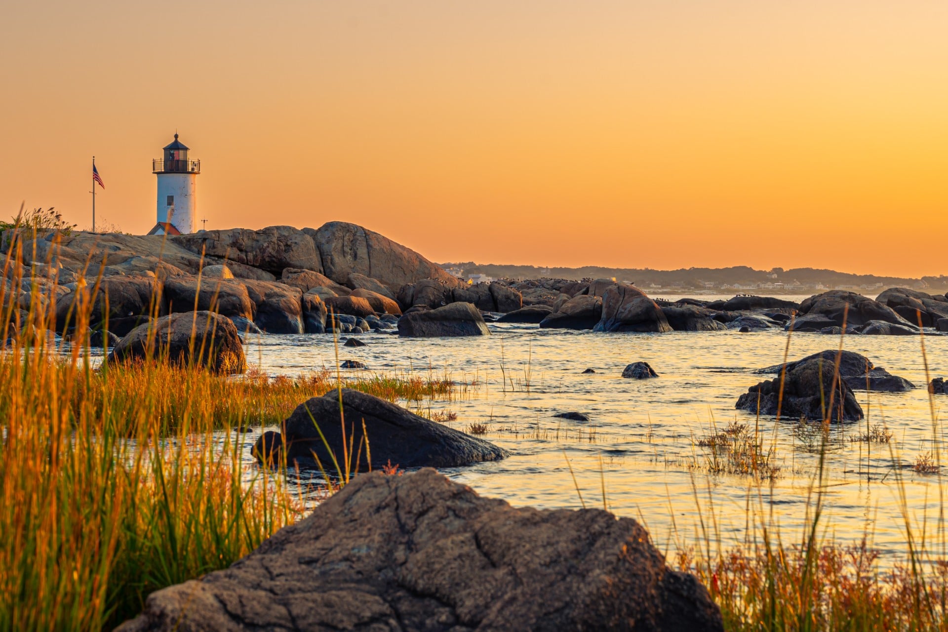 Photograph of a lighthouse on rocky shores at sunset