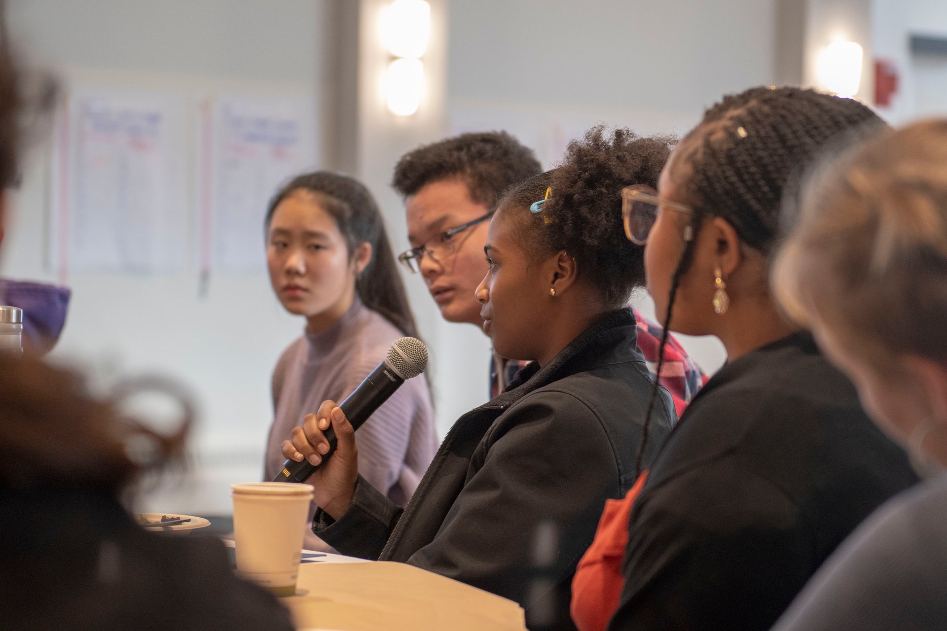 Young adults at a table, one speaking into a mic