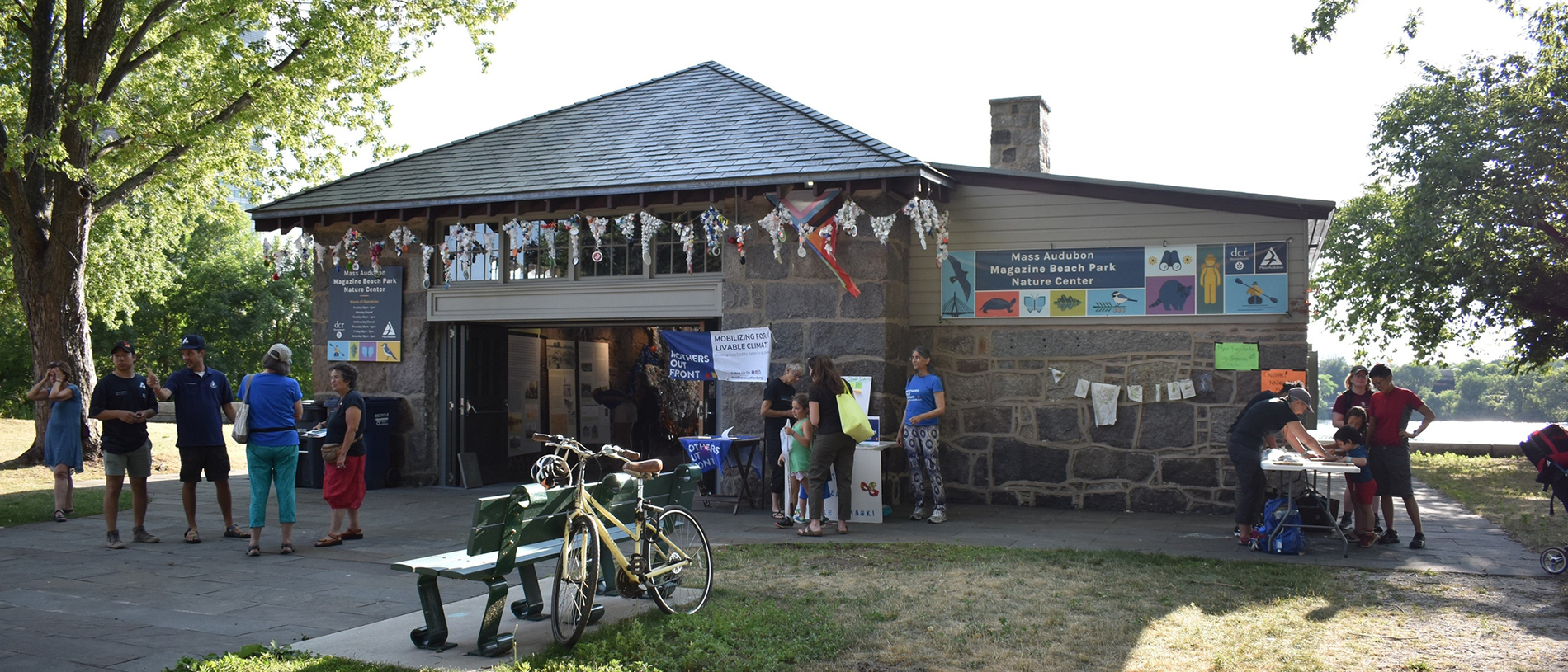 Magazine beach building with people out front and a bicycle next to a bench