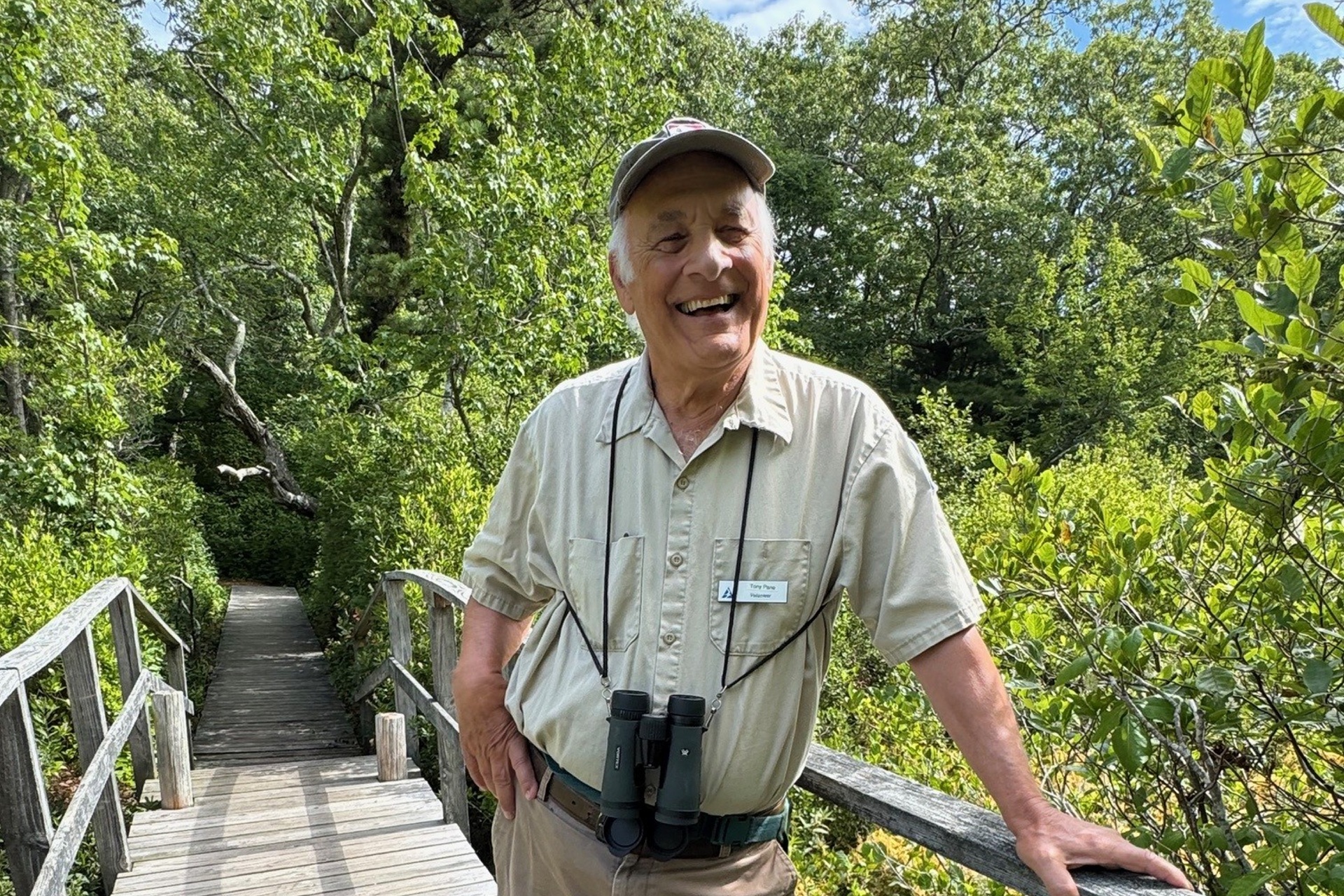 Wellfleet Bay volunteer Tony Pane leaning on a boardwalk railing