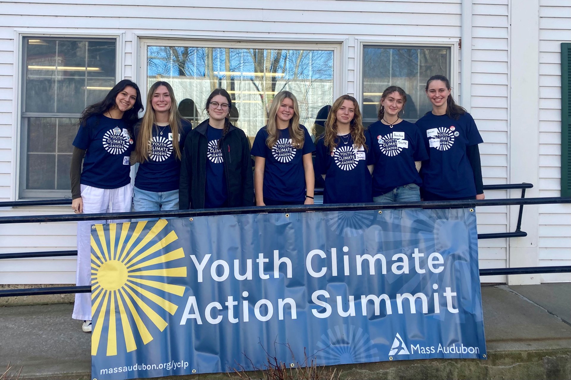 Group of Youth Climate Action Summit attendees posing for a picture behind a banner of the same name