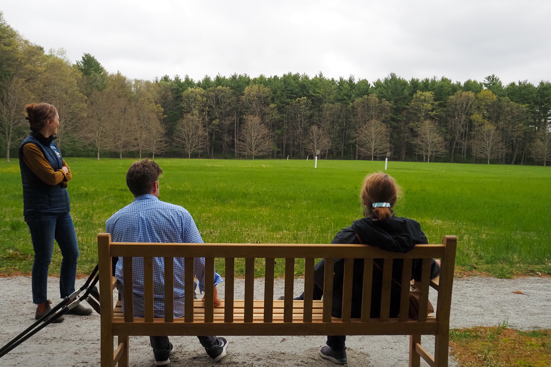 A small group of people on the All Persons Trail. Two are seated on a wooden bench.