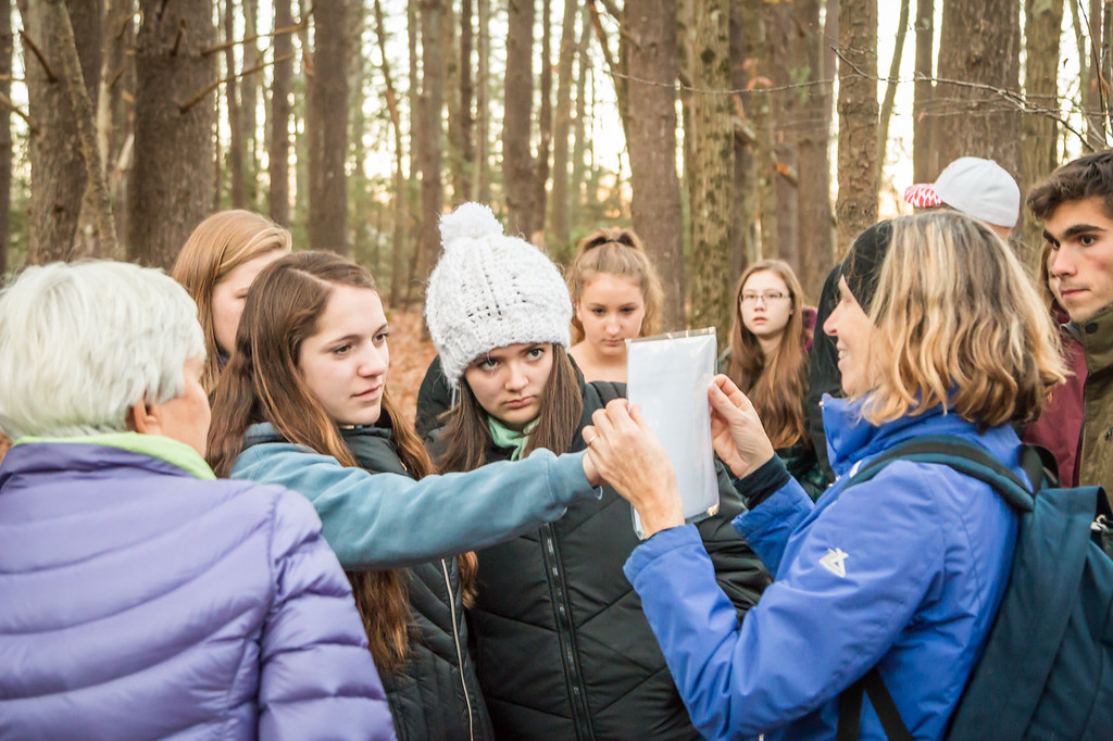 High school students with teachers outside - one student pointing to a piece of paper