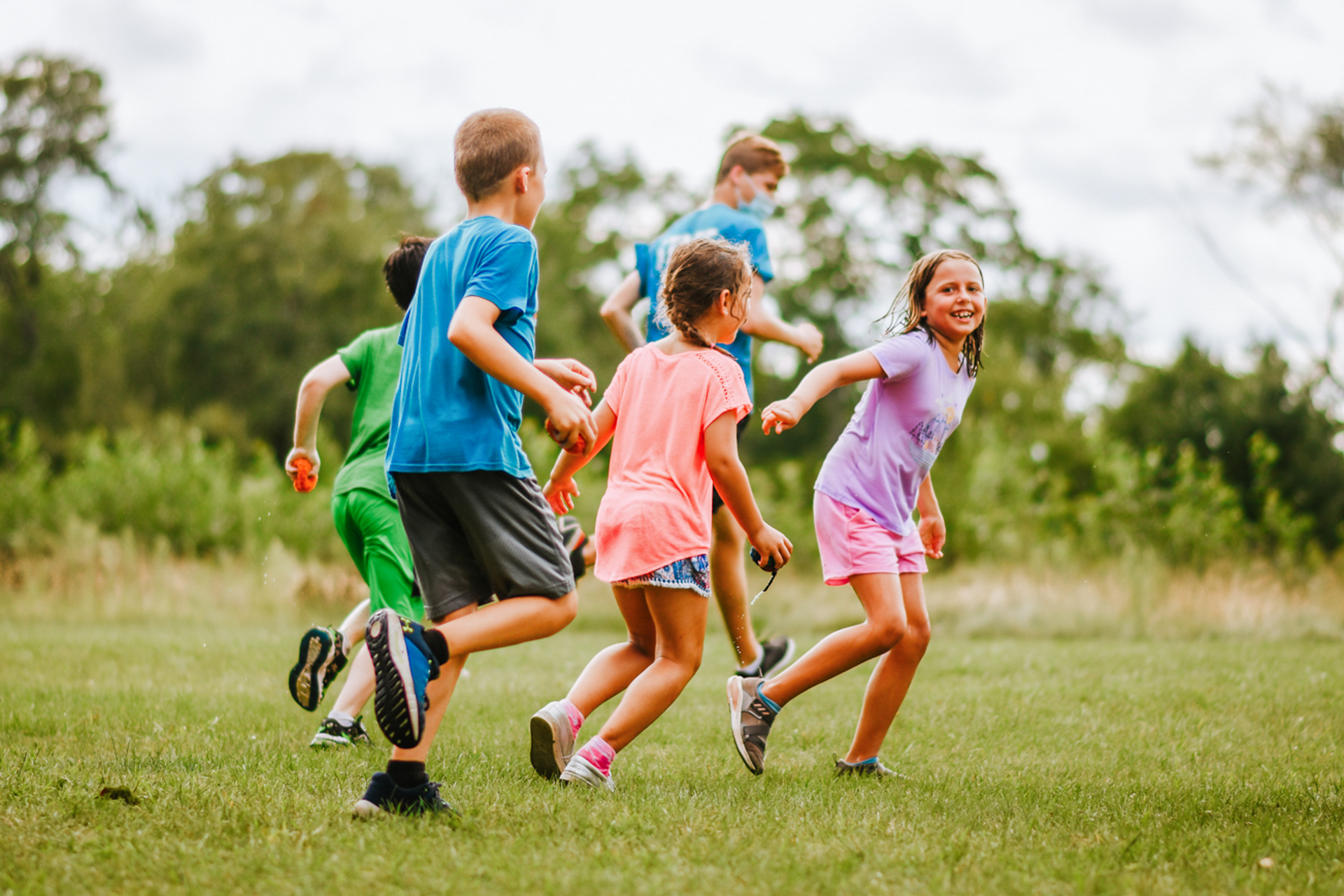 A group of campers at Stony Brook playing field games, running and smiling