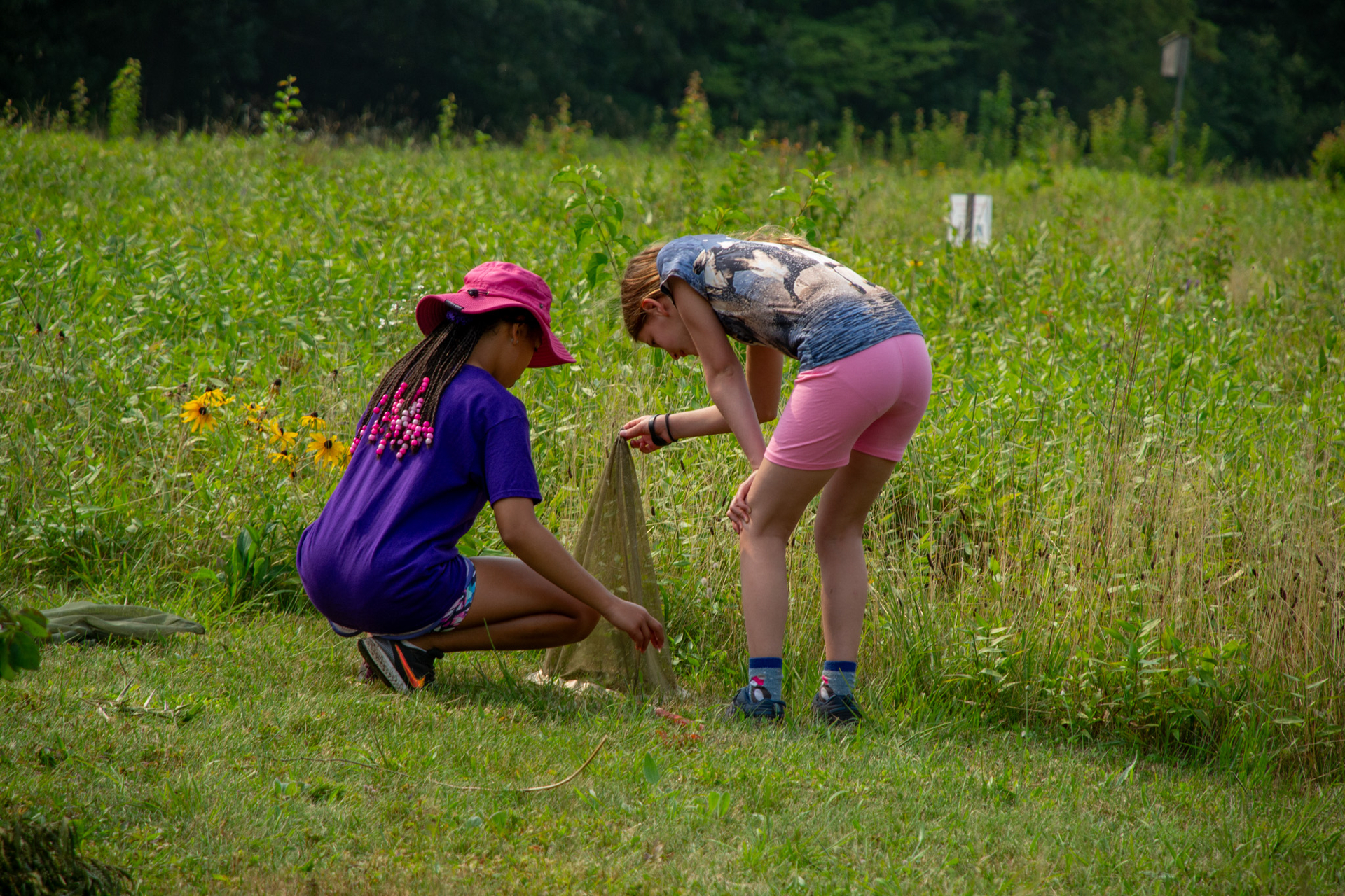 two campers hold up a net in the corner of a field to see whats inside.