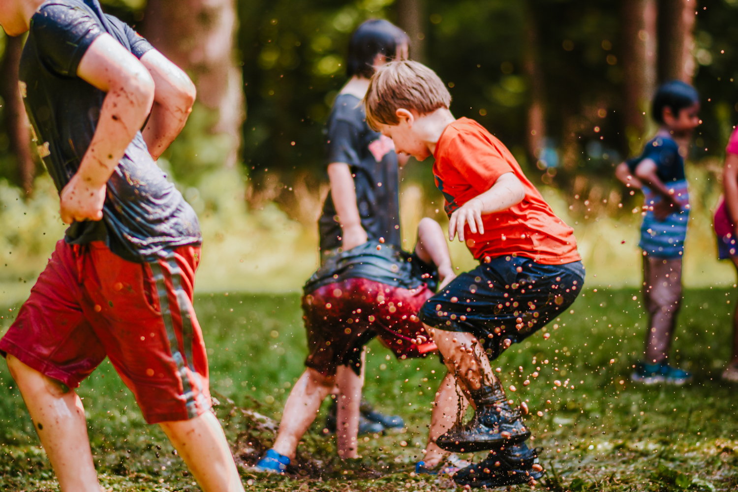A camper stomps and splashes in the mud at Moose Hill Nature Camp