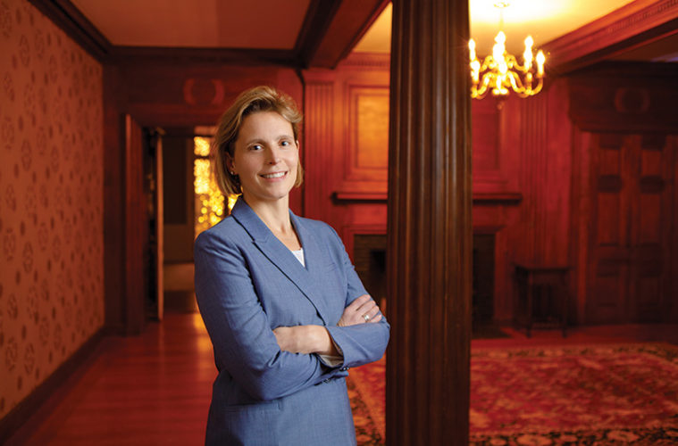 Jocelyn Forbush standing in a dark room with arms crossed smiling at the camera