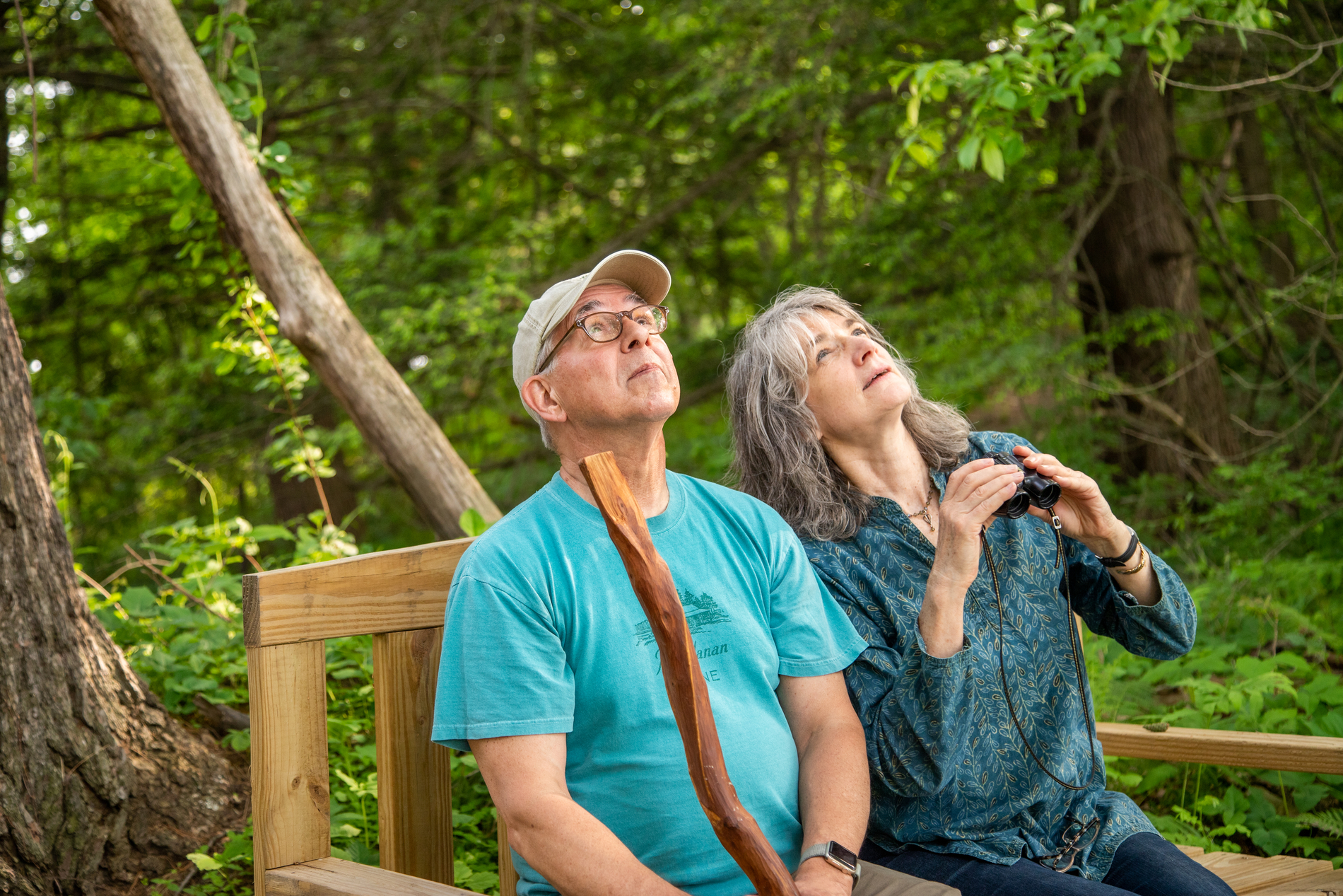 Two birders sitting on bench looking up