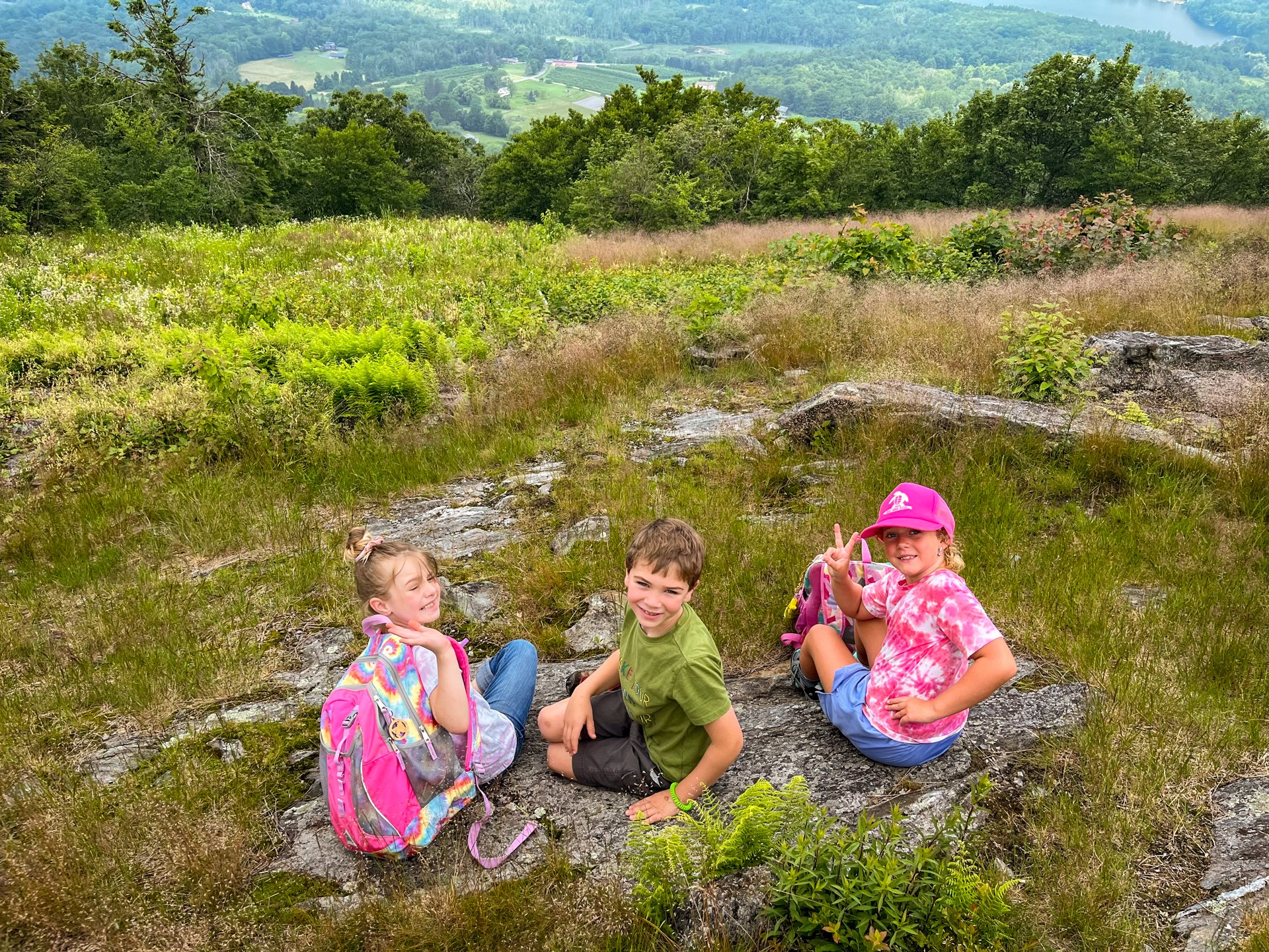 Three campers at Berkshire Nature Camp smile for the camera while enjoying a scenic vista after a long hike at Pleasant Valley