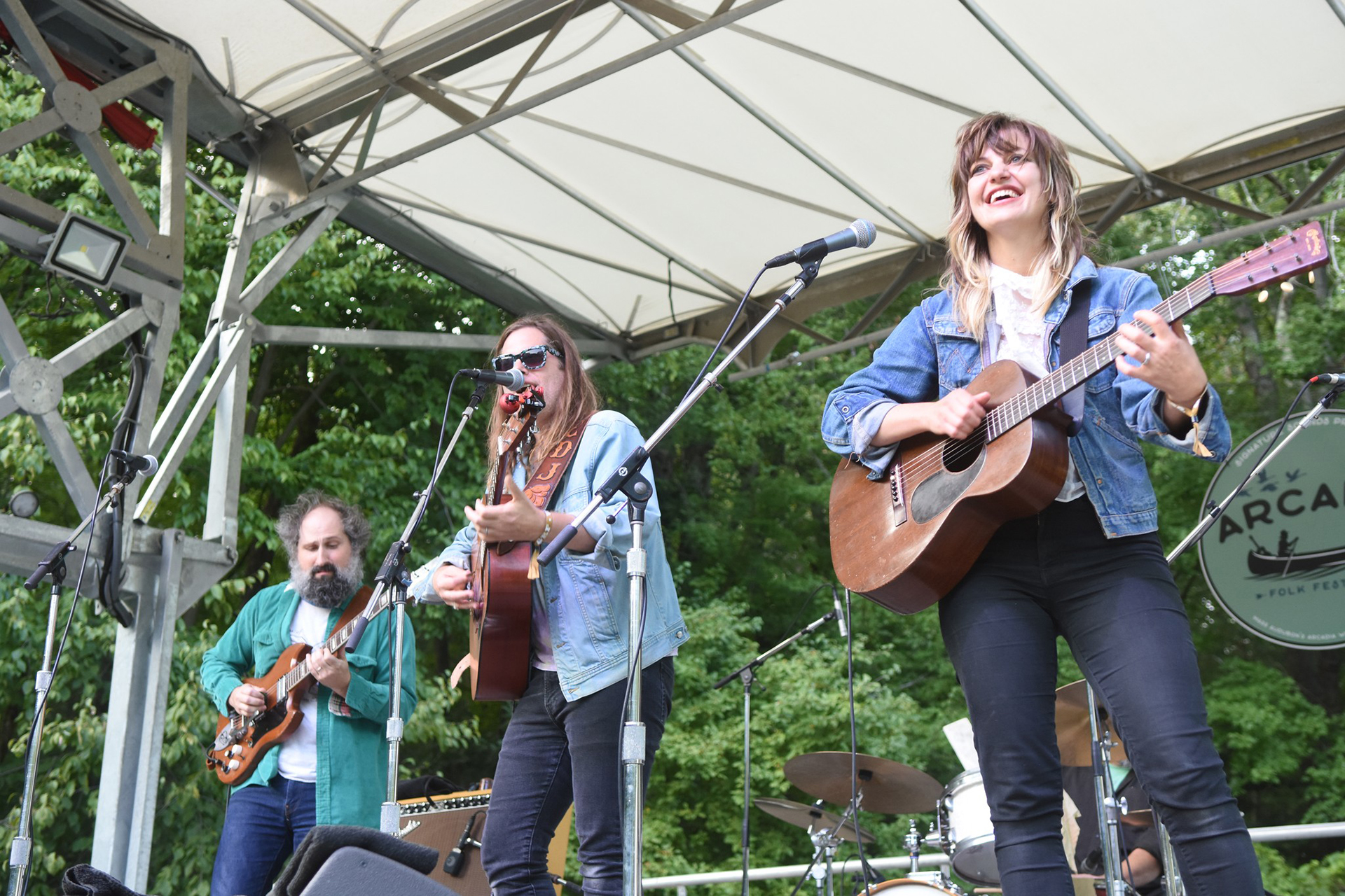 three musicians playing guitar on stage