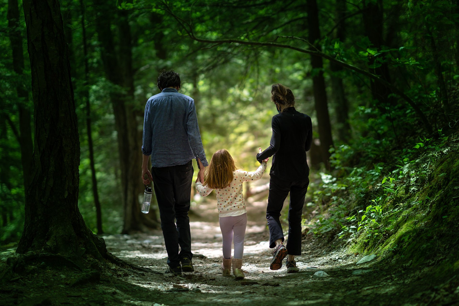 two people with child on shaded trail