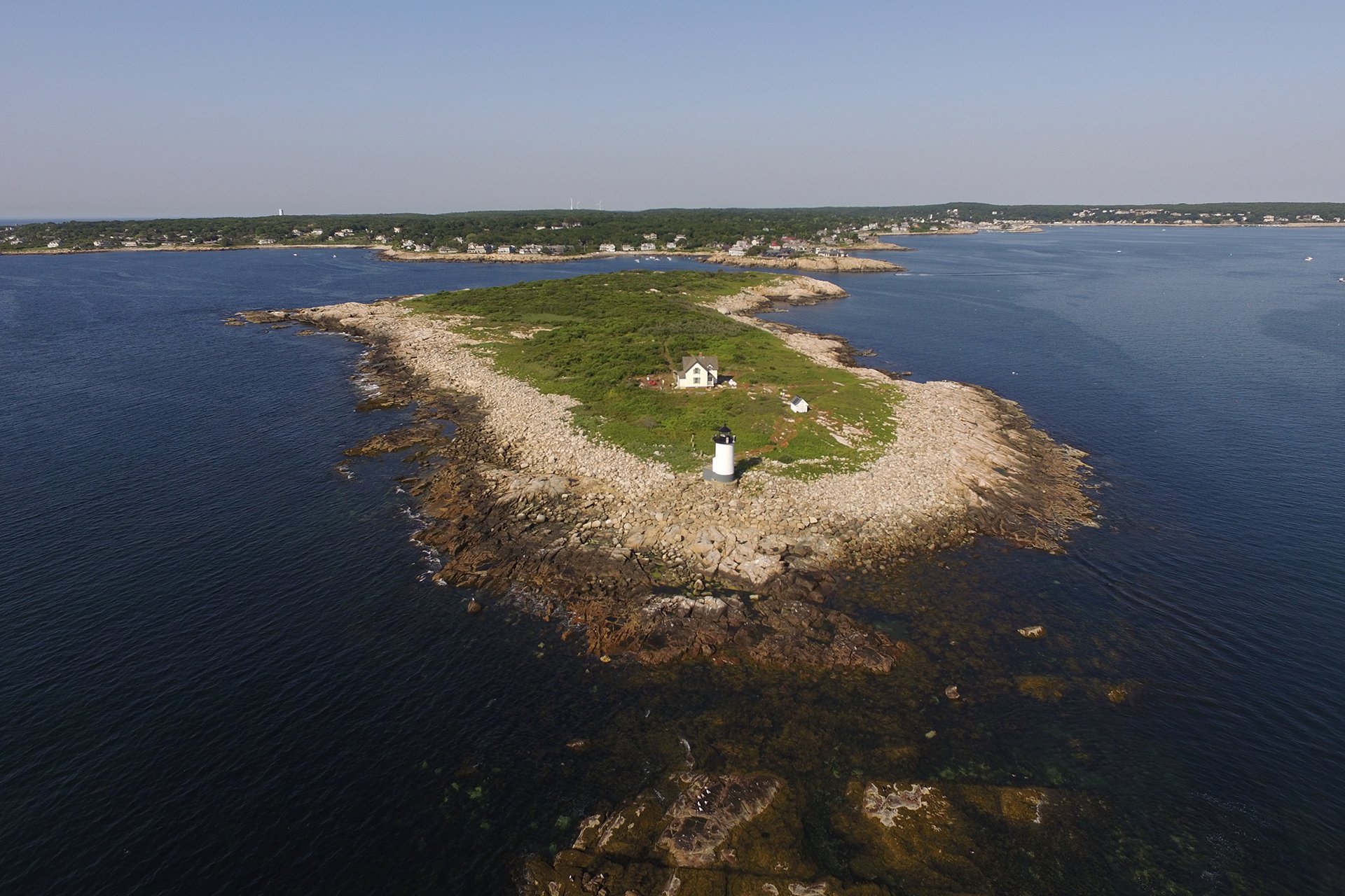 Aerial view of island - rocky shore, lighthouse, and green center