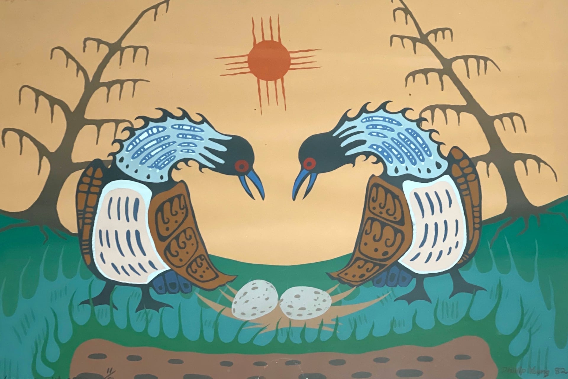 A wood carving of two loons looking down on two speckled eggs.