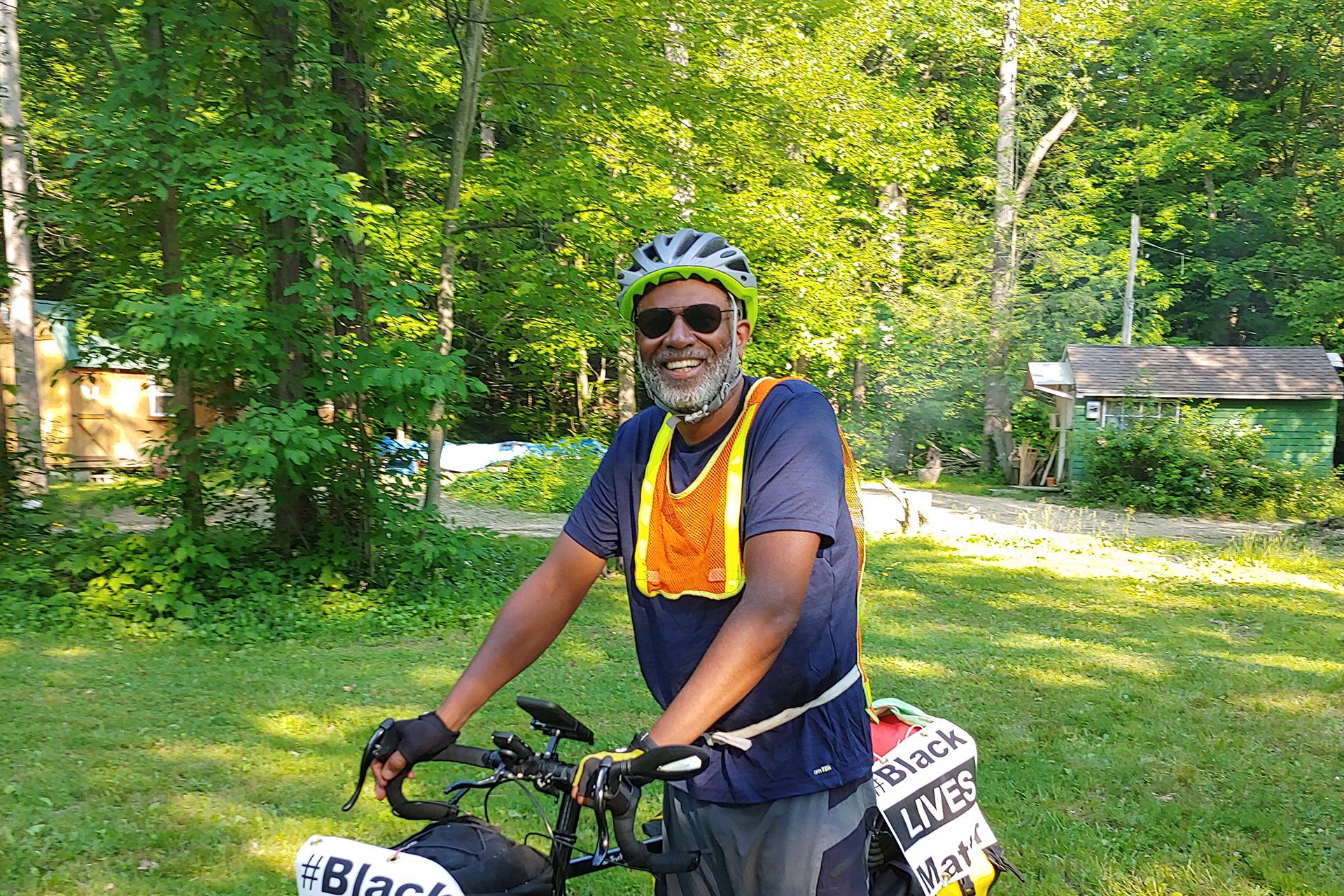 Man standing next to a bike with a "Black Lives Matter" sign taped to the front and sides.