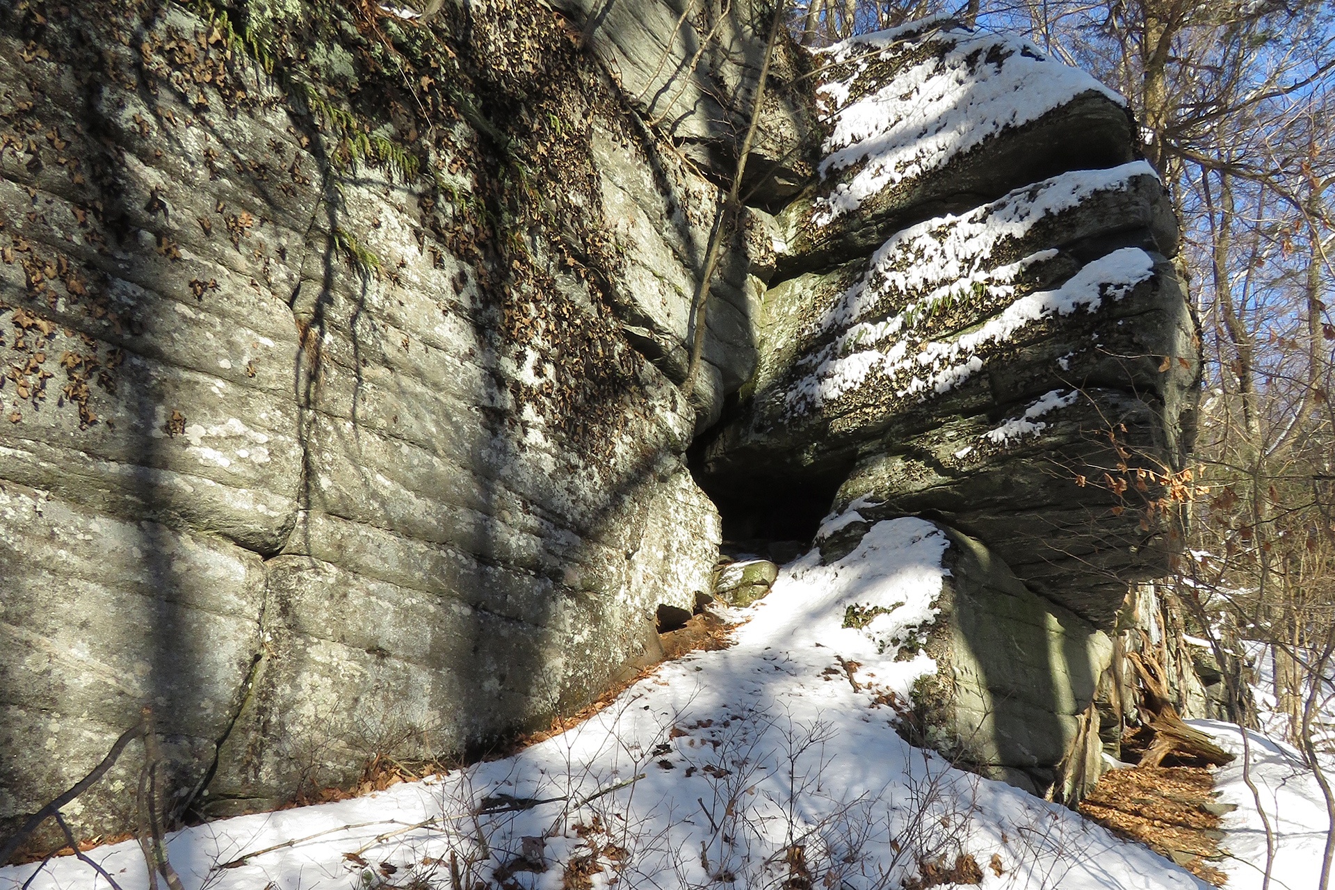 Small, cave-like hole in a rock formation, covered in sparse snow