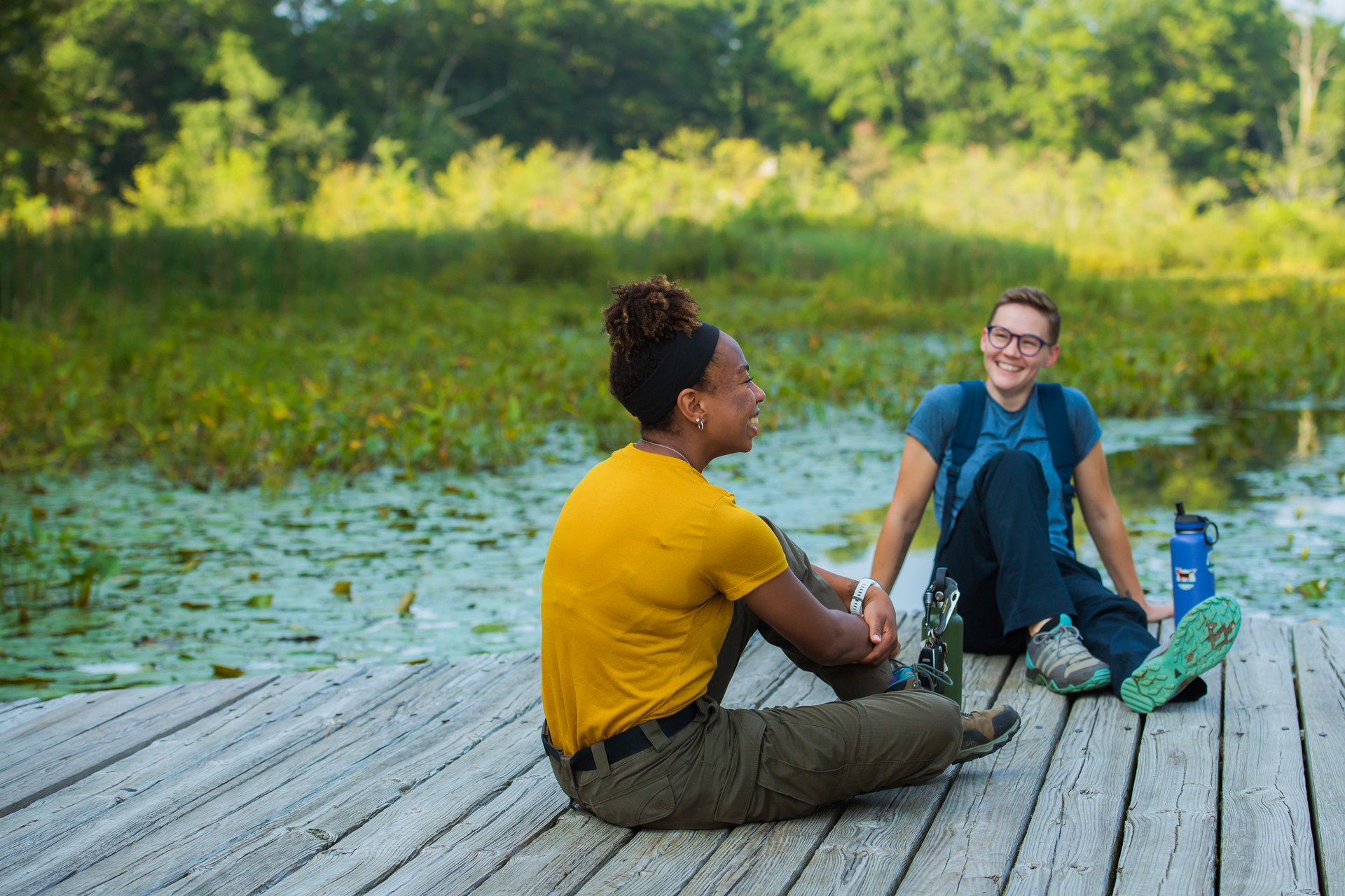 Two people sitting on a boardwalk at a wildlife sanctuary