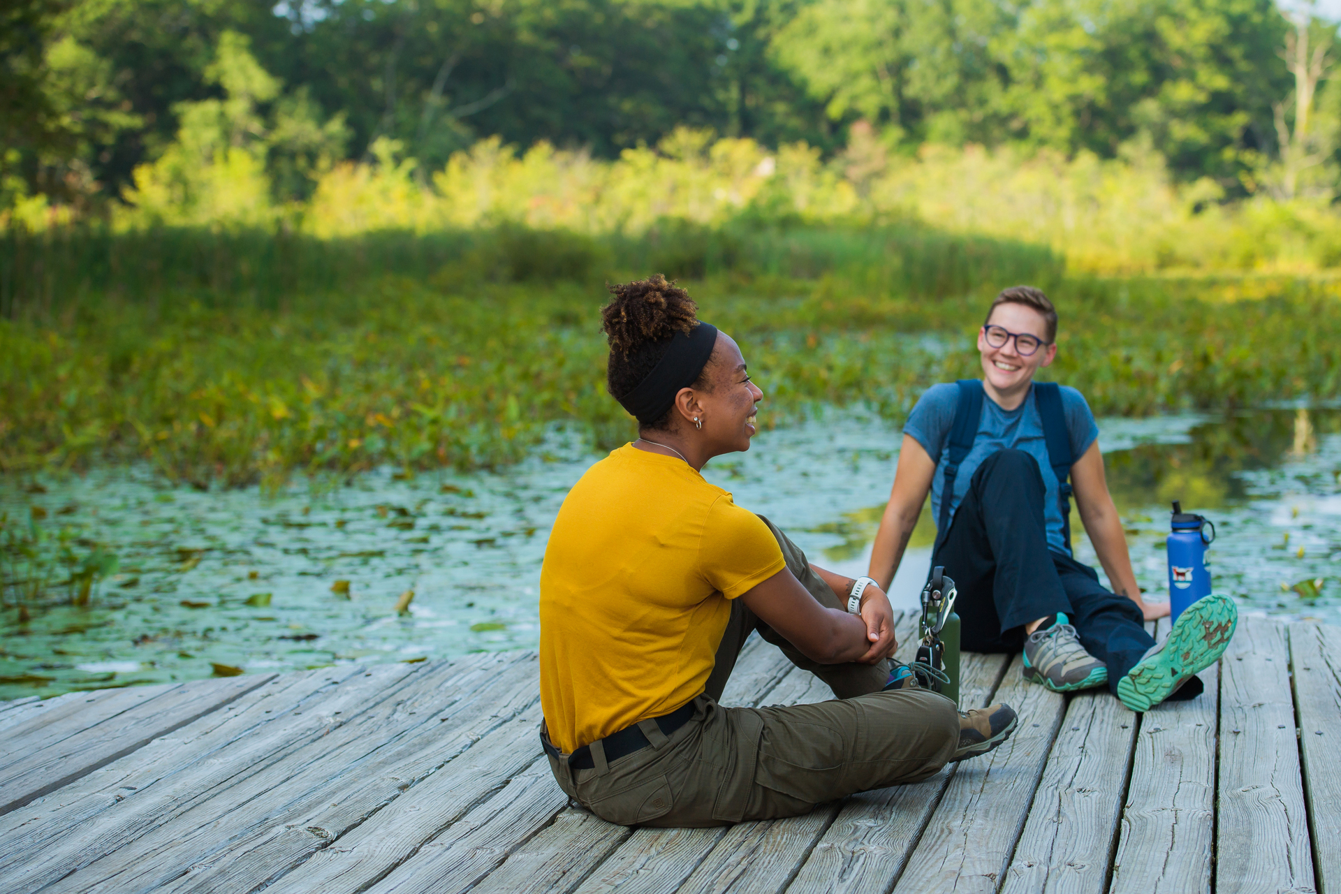 Two people sitting on a boardwalk at a wildlife sanctuary