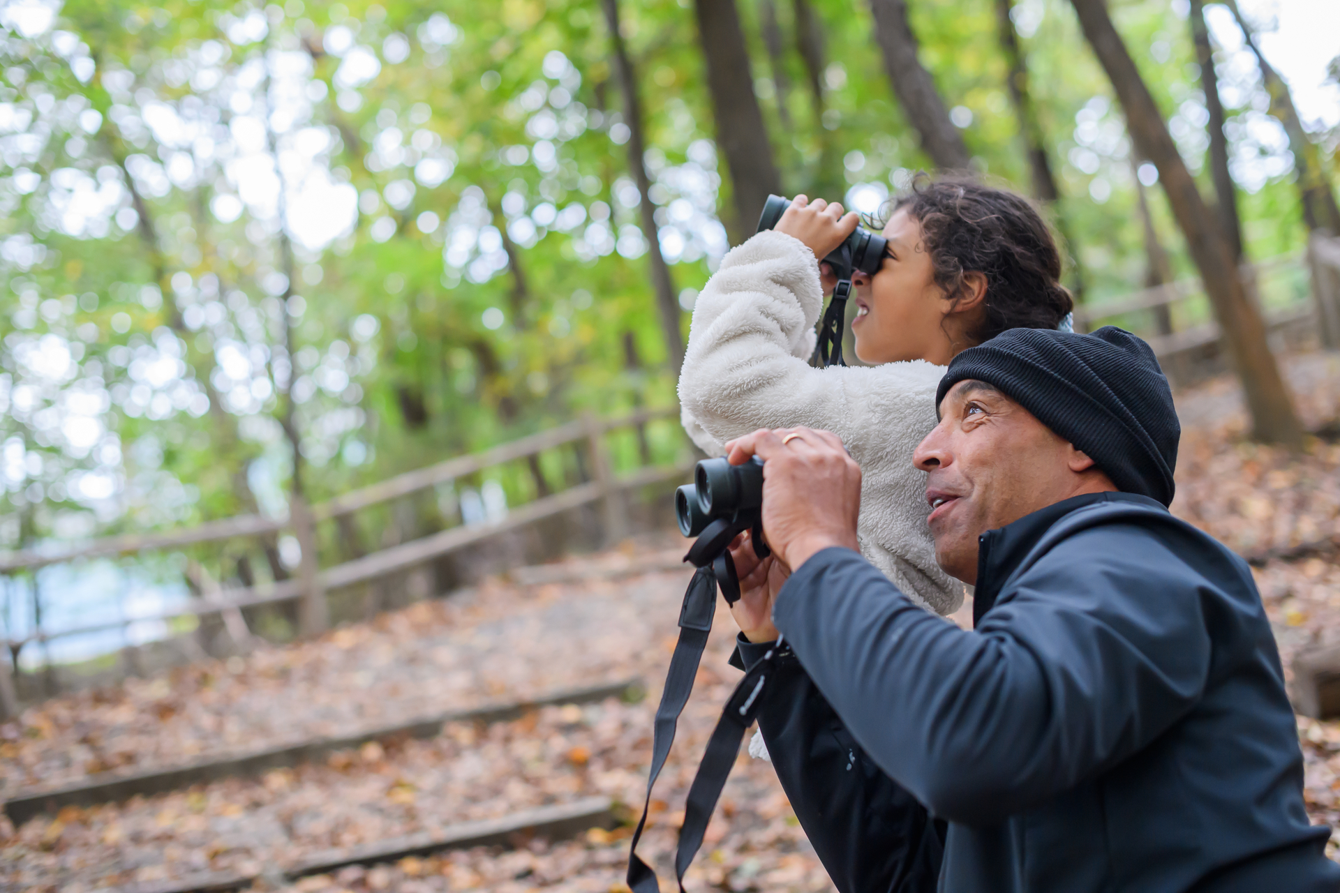 Man and child looking up through binoculars