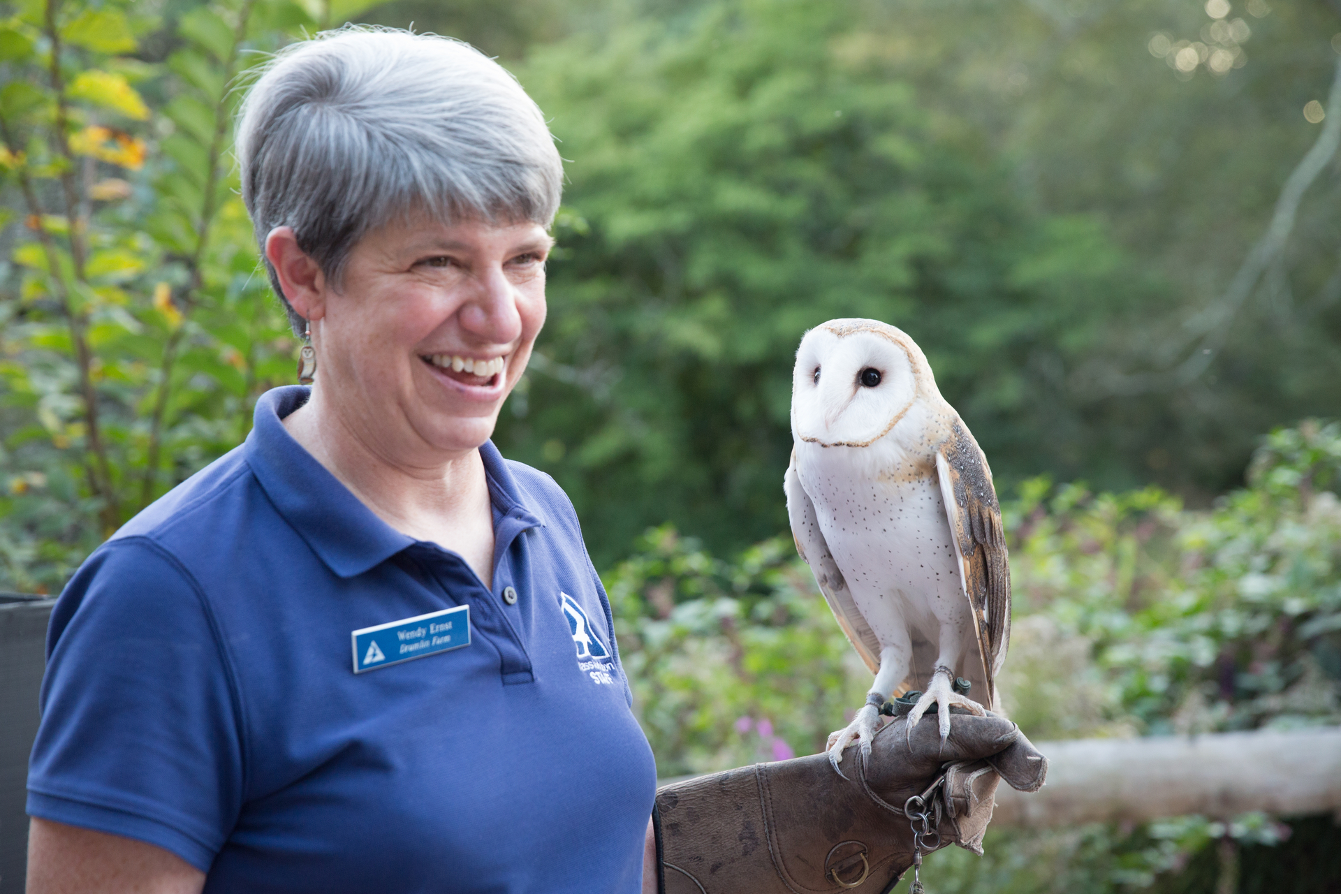 Mass Audubon staff smiling and holding owl